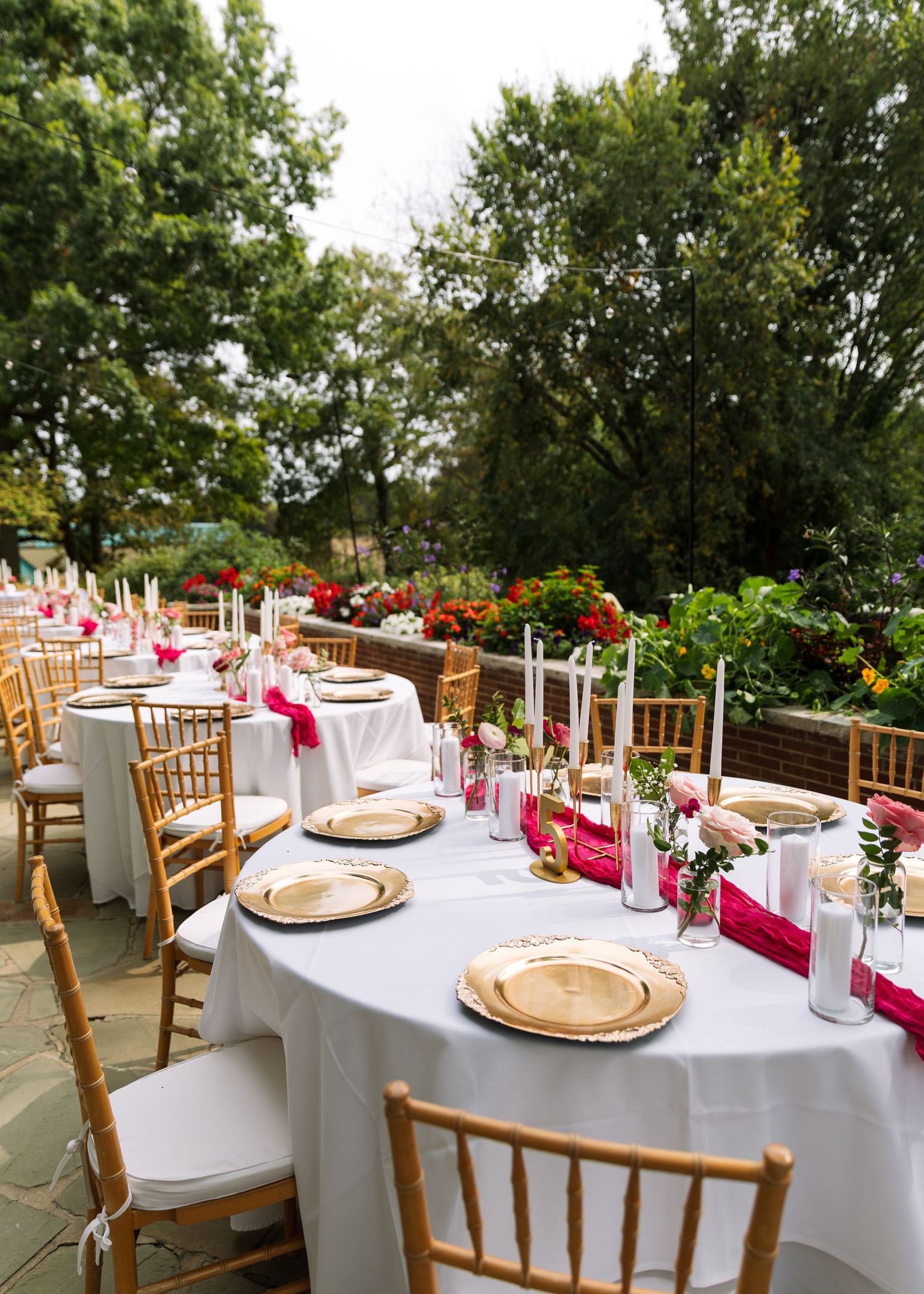 Elegant wedding reception table settings with gold chargers and pink floral centerpieces.
