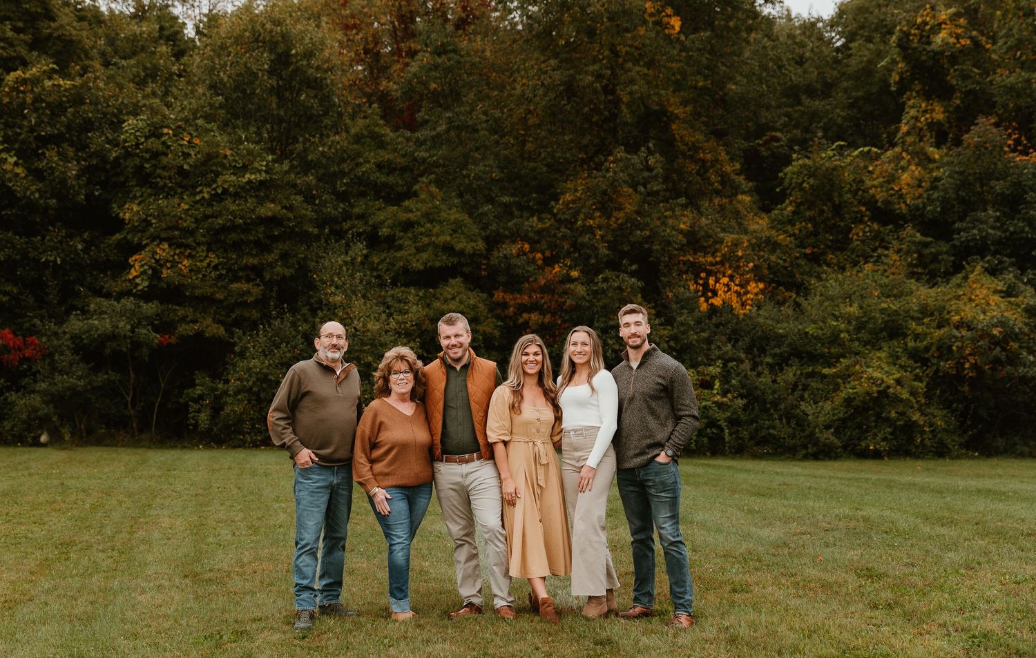 Wide panoramic view of a group walking together on a grassy hill during autumn.