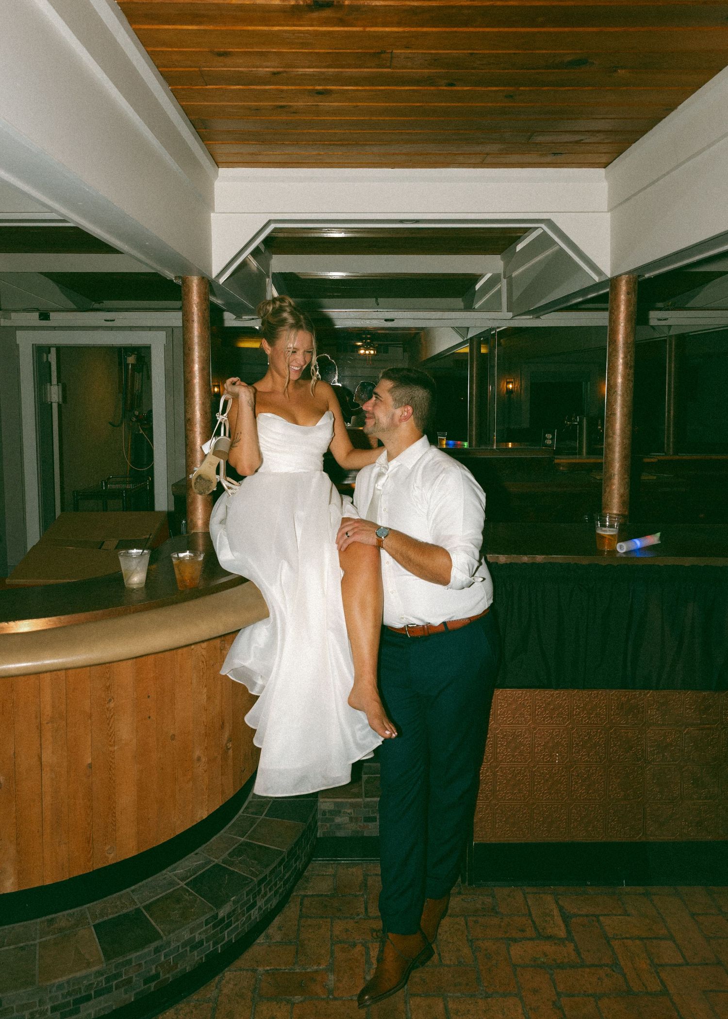 Wedding couple performs fun dance moves in a wood-paneled reception venue.