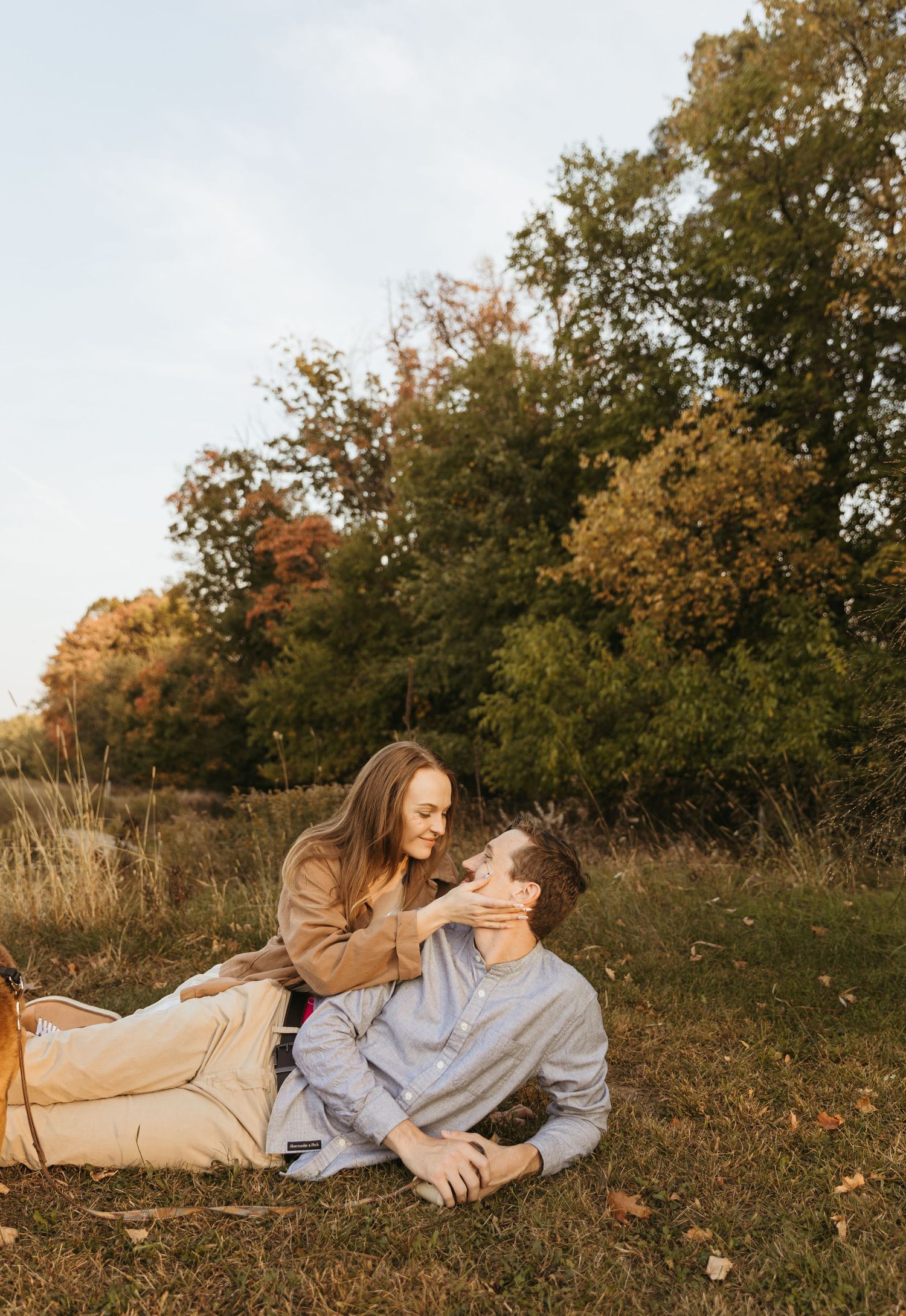 Couple enjoying a playful moment in a autumn field with warm golden light.