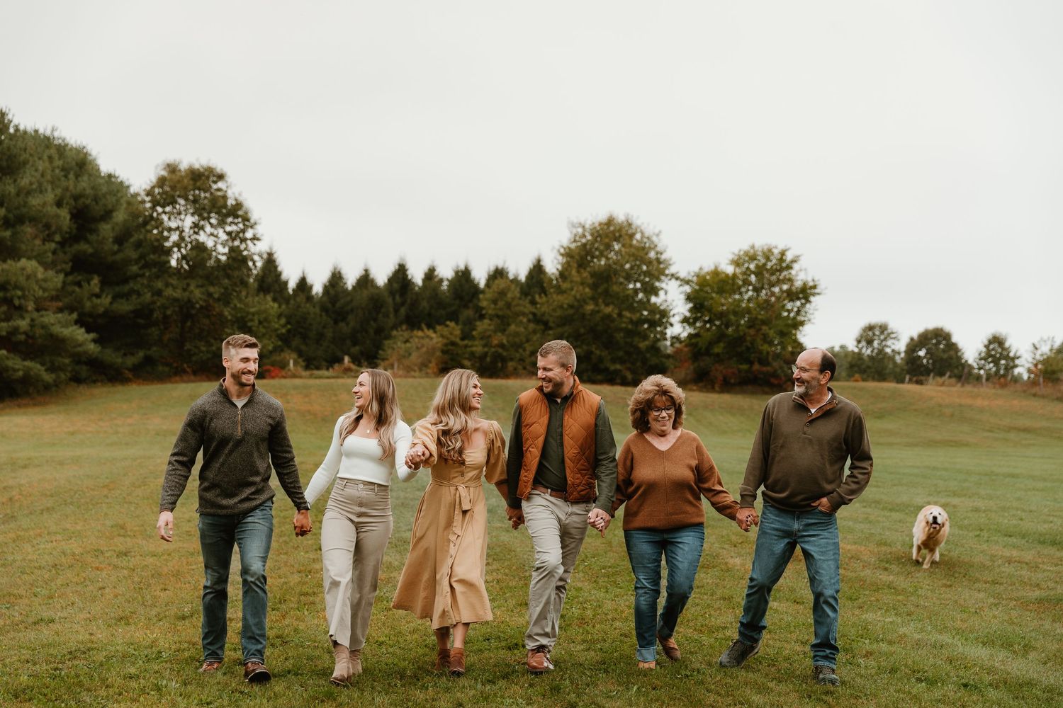 Candid shot of people walking together across a grassy hillside with a dog.