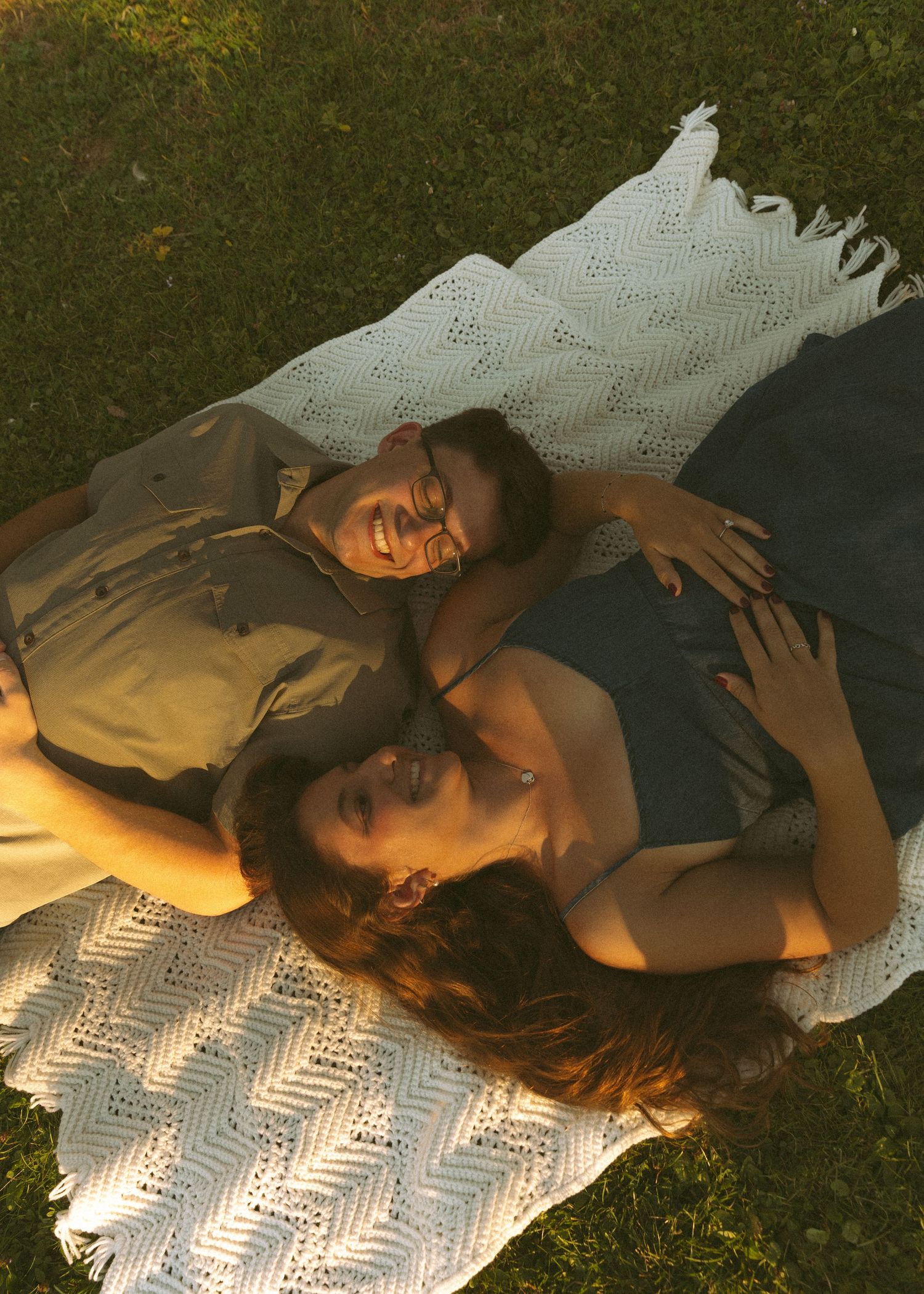 A couple lying on a blanket with a chevron pattern outdoors.