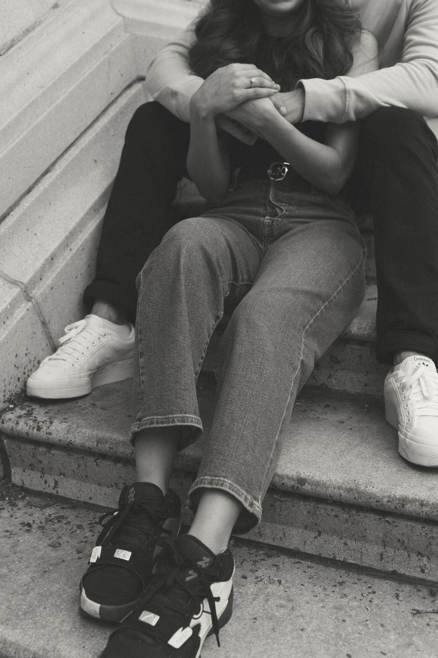 A close-up shot of people sitting on concrete steps wearing casual denim and sneakers.