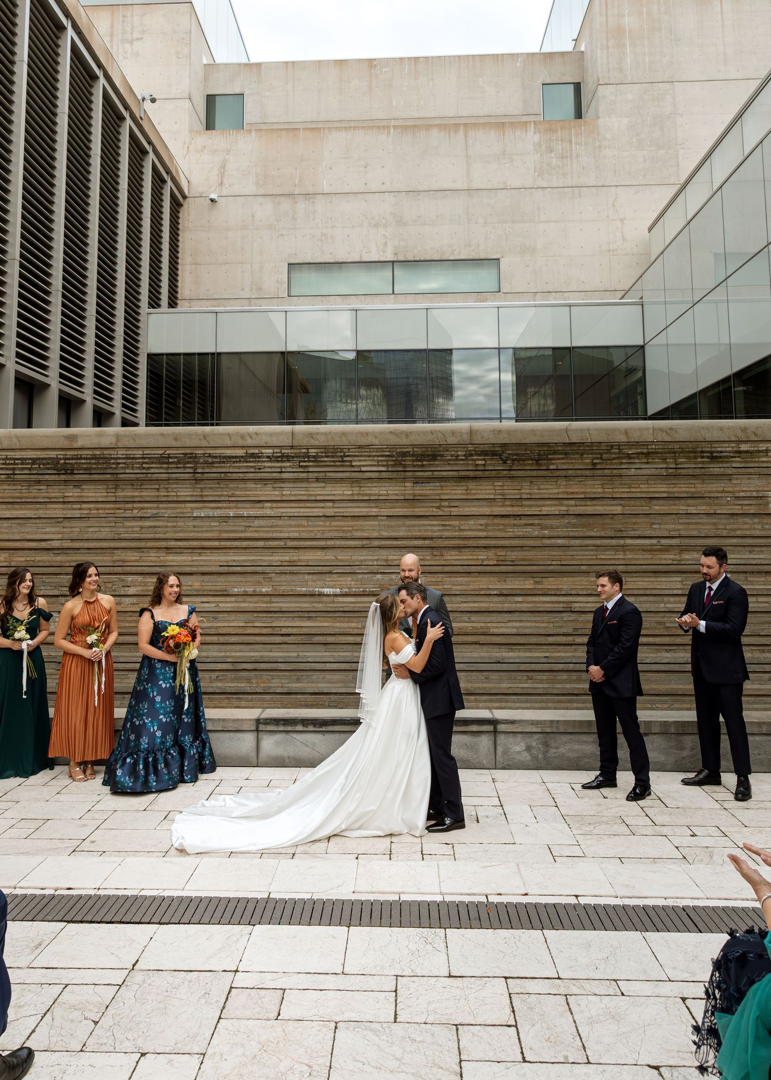Wedding party poses on modern concrete steps outside a contemporary building.
