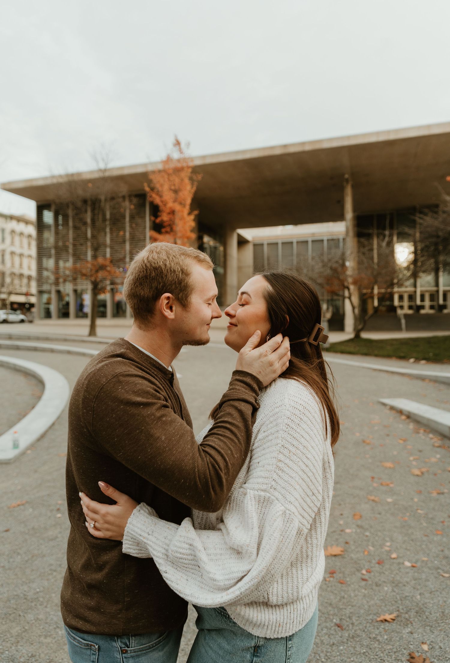A tender moment between a couple wearing sweaters outside on an autumn afternoon.