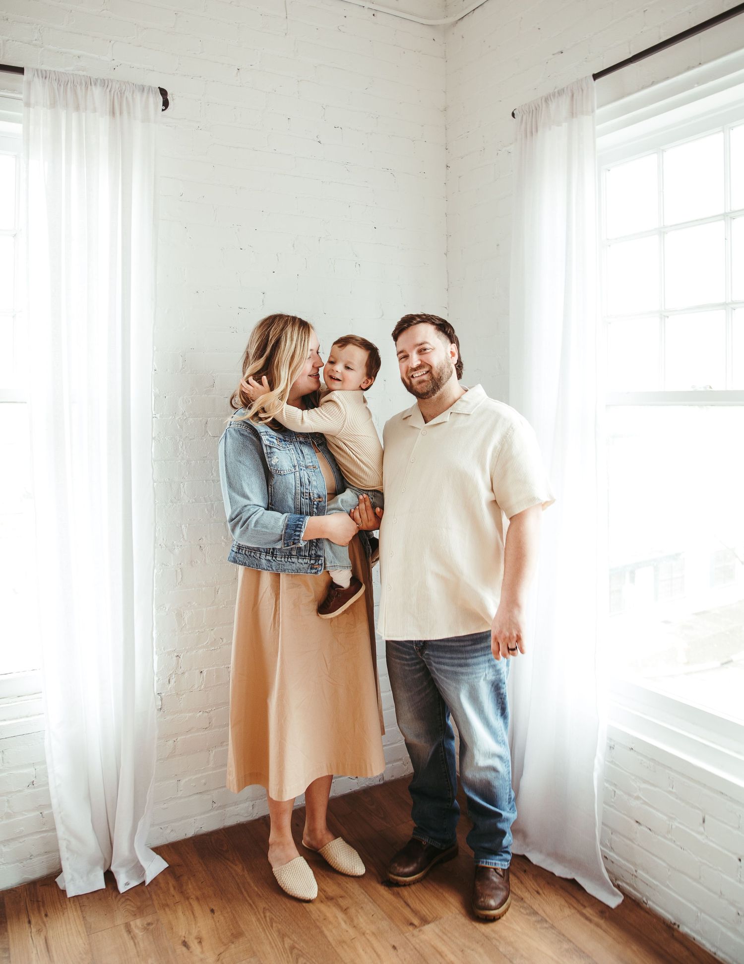 Happy family playing and laughing together in bright white room.