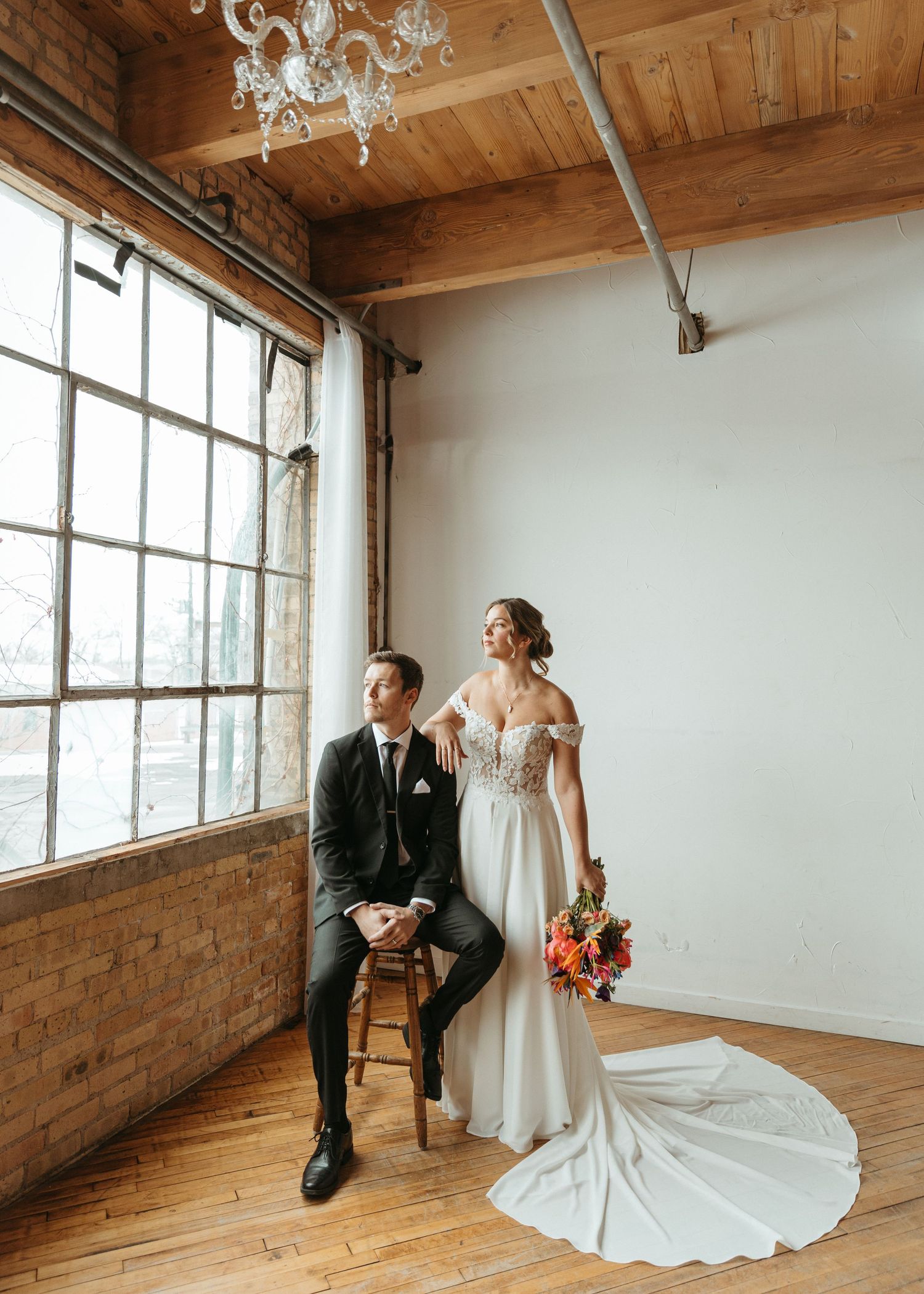 Industrial loft wedding portraits with elegant couple against exposed brick and large windows.