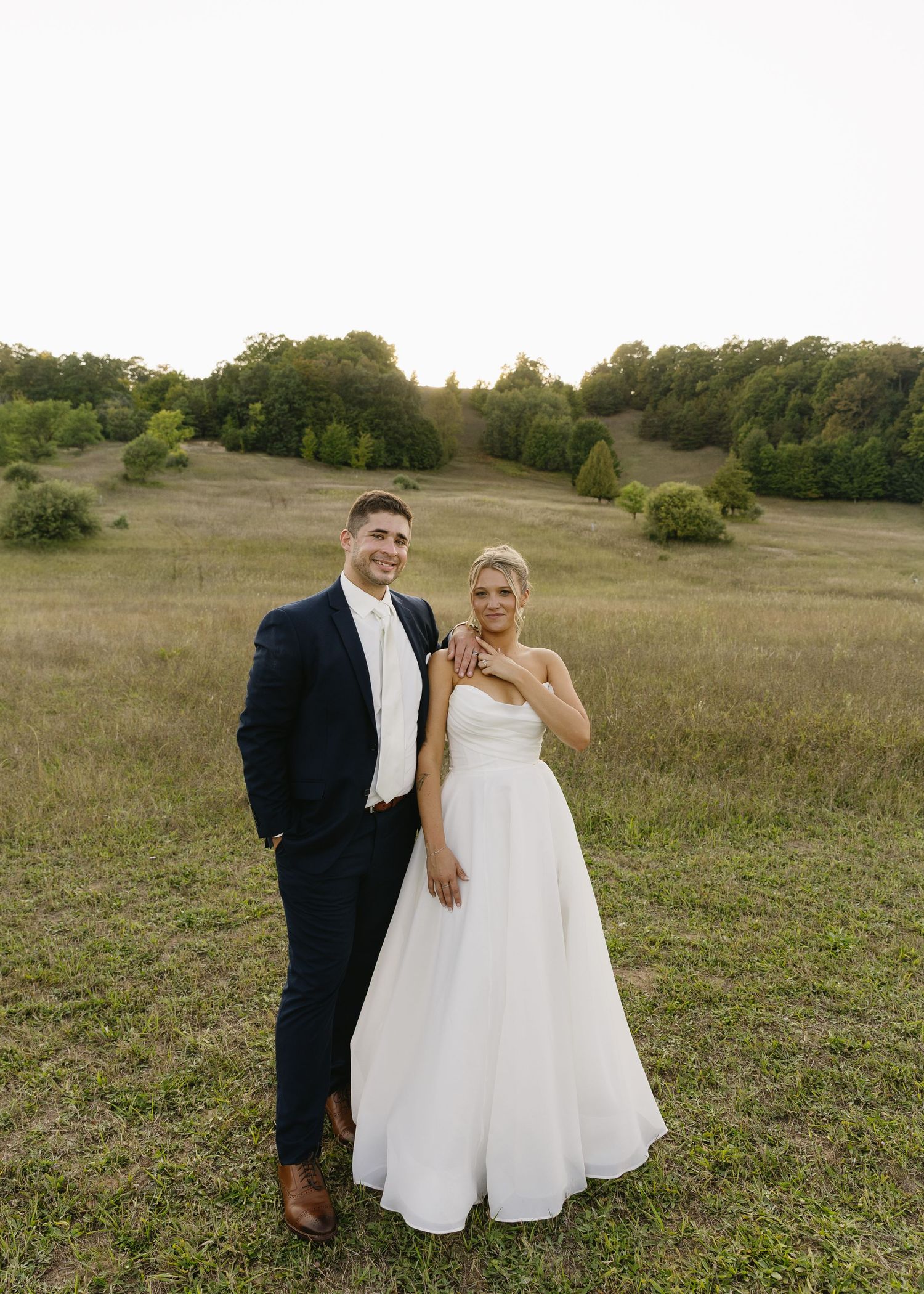 A couple shares joyful moments together in an open meadow during their wedding photoshoot.