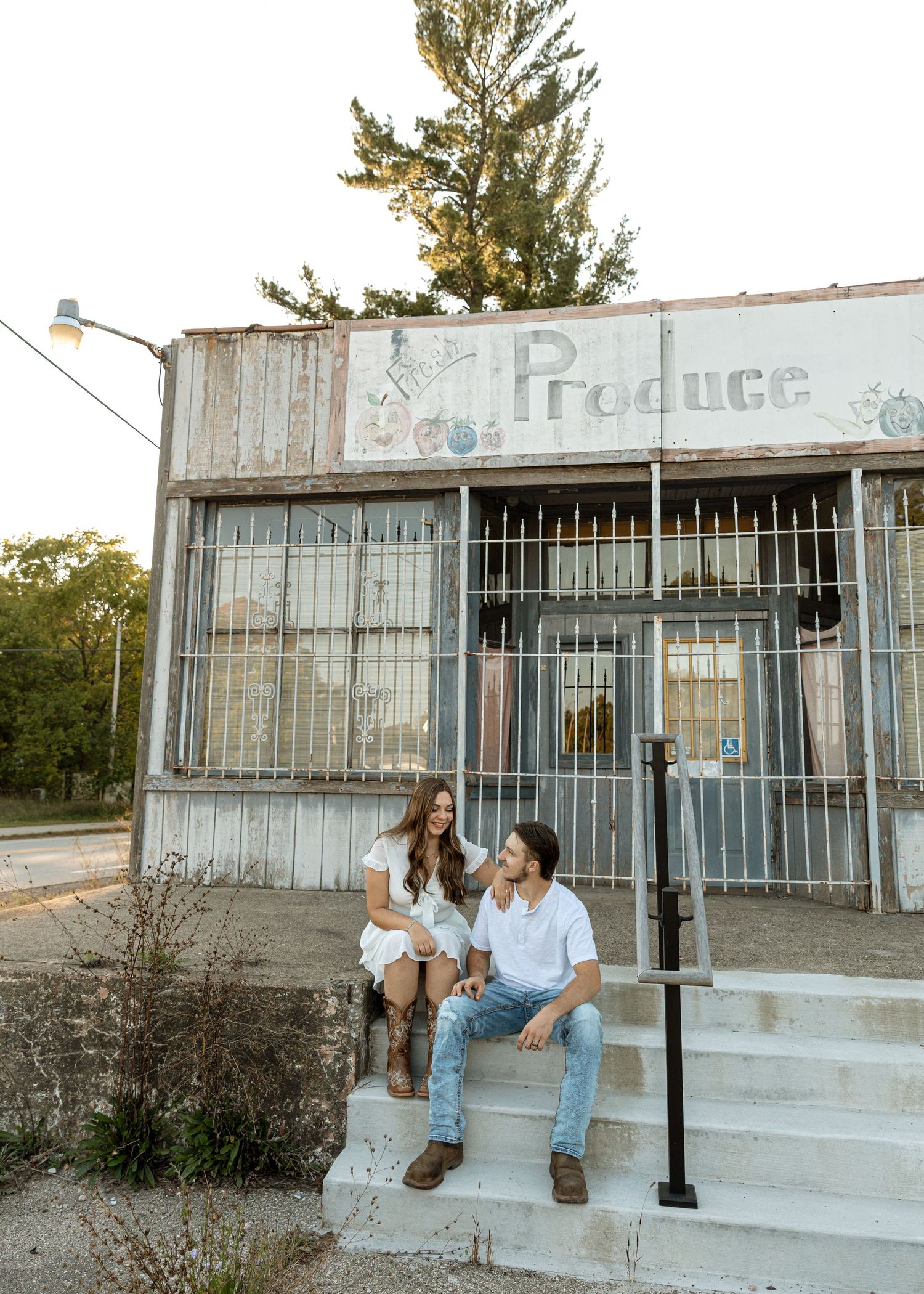 Couple shares intimate moment on steps of abandoned storefront.