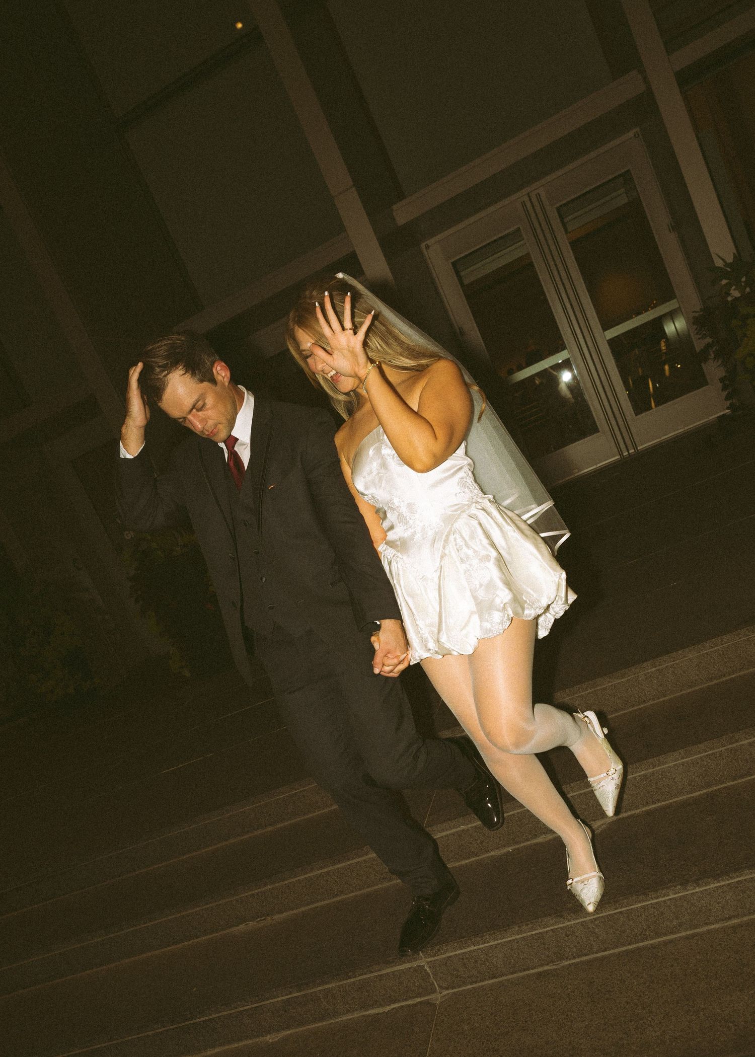 Wedding party members pose playfully in a dark hallway setting.