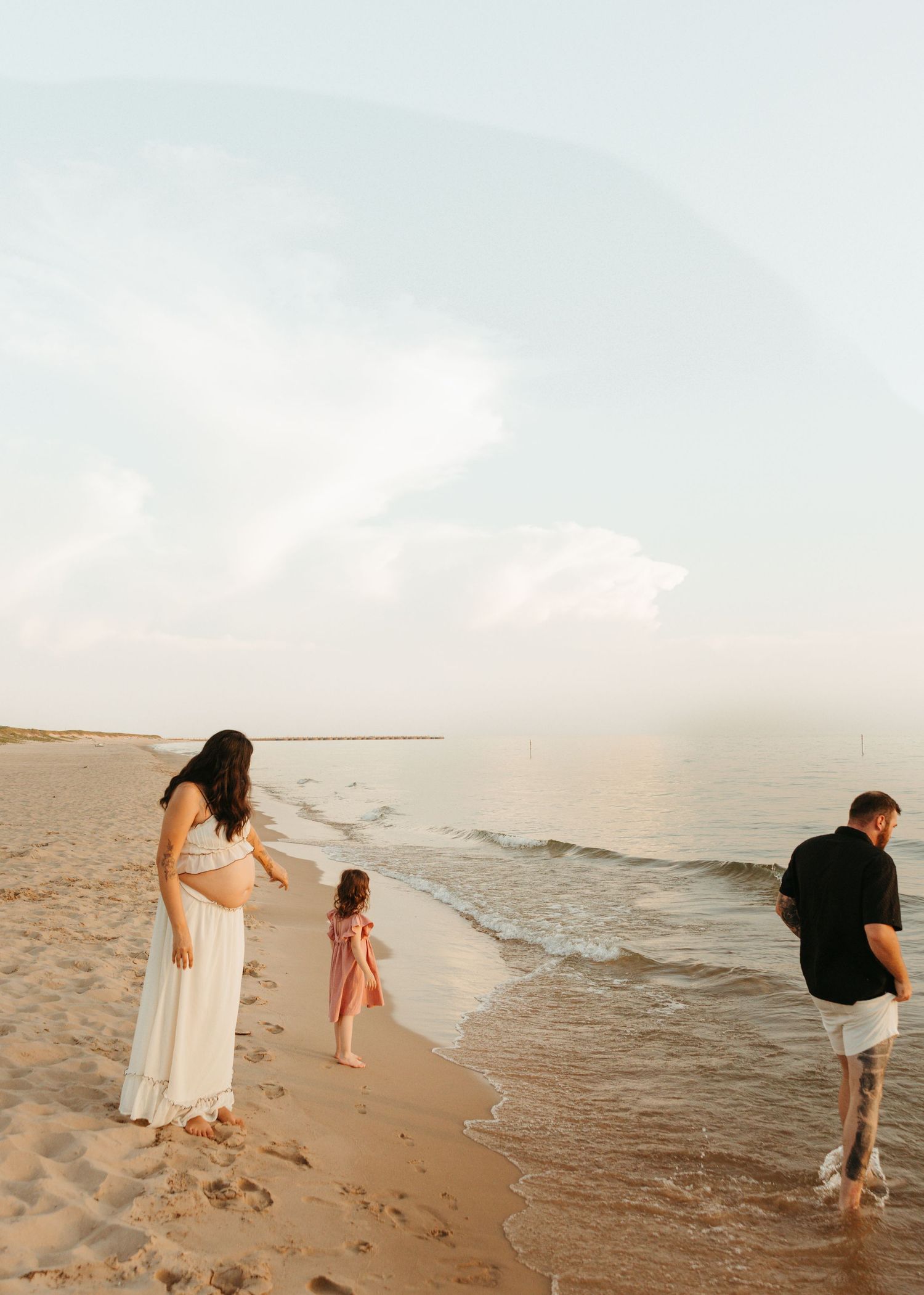 A family plays together along the shoreline during sunset.