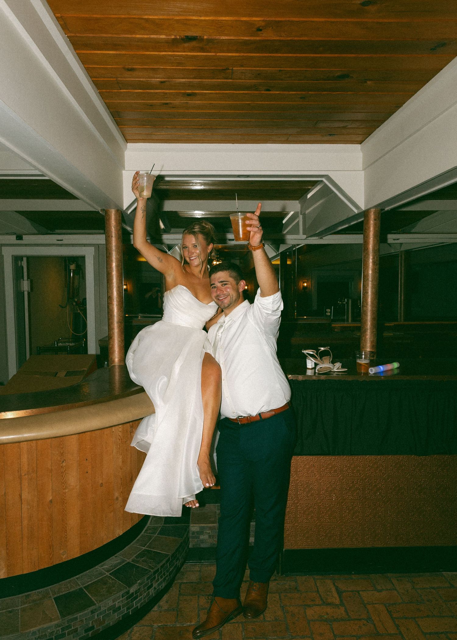 Playful dancing moments captured in a rustic indoor venue with wooden ceiling.