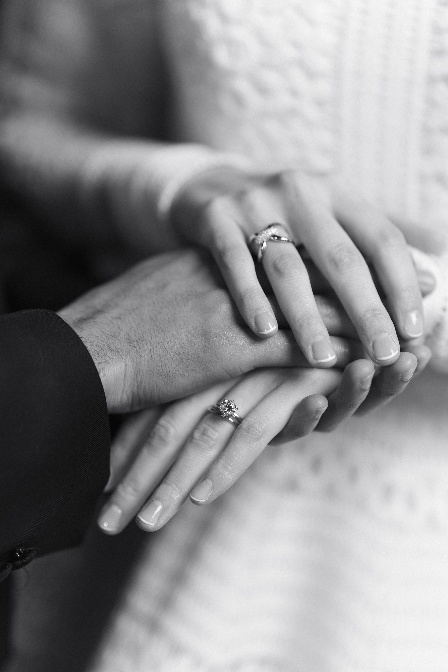 Close-up black and white photo of hands with wedding rings touching.
