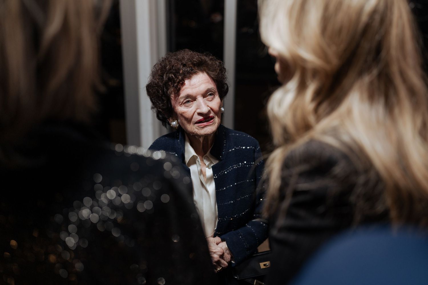 A candid conversation captured during an evening gathering indoors.