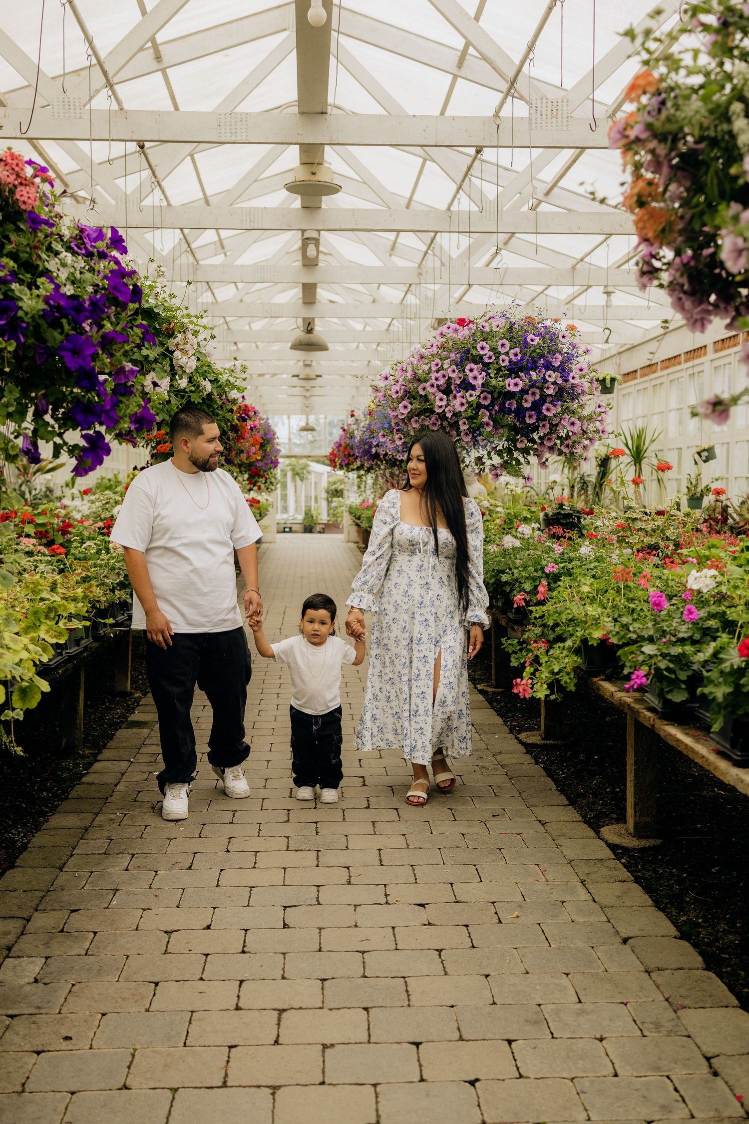 Greenhouse interior walkway with colorful hanging flower baskets and stone paver flooring showing five consecutive scenes.