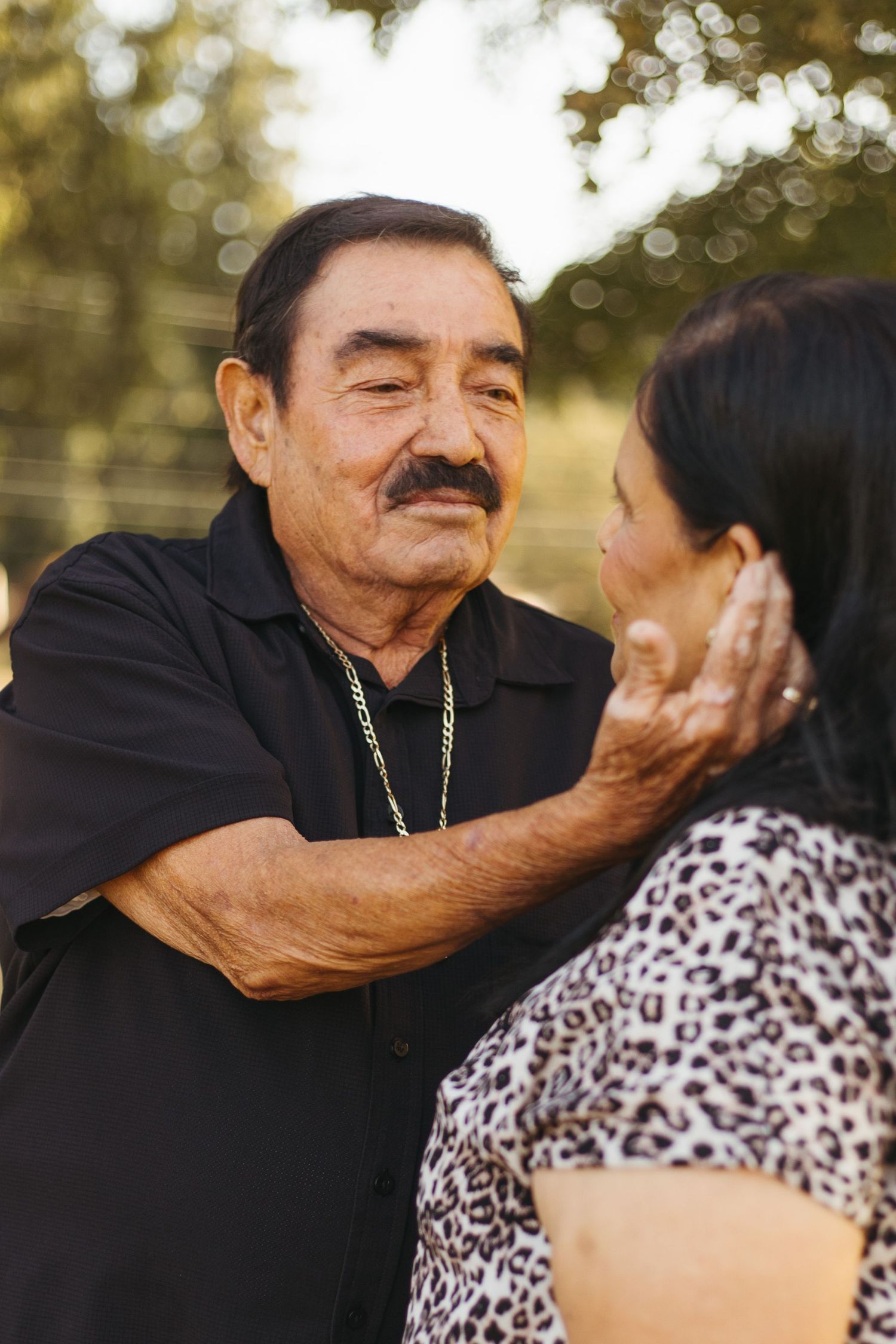 Elderly couple in black and leopard print share tender moments in a sequence of intimate outdoor portrait shots.