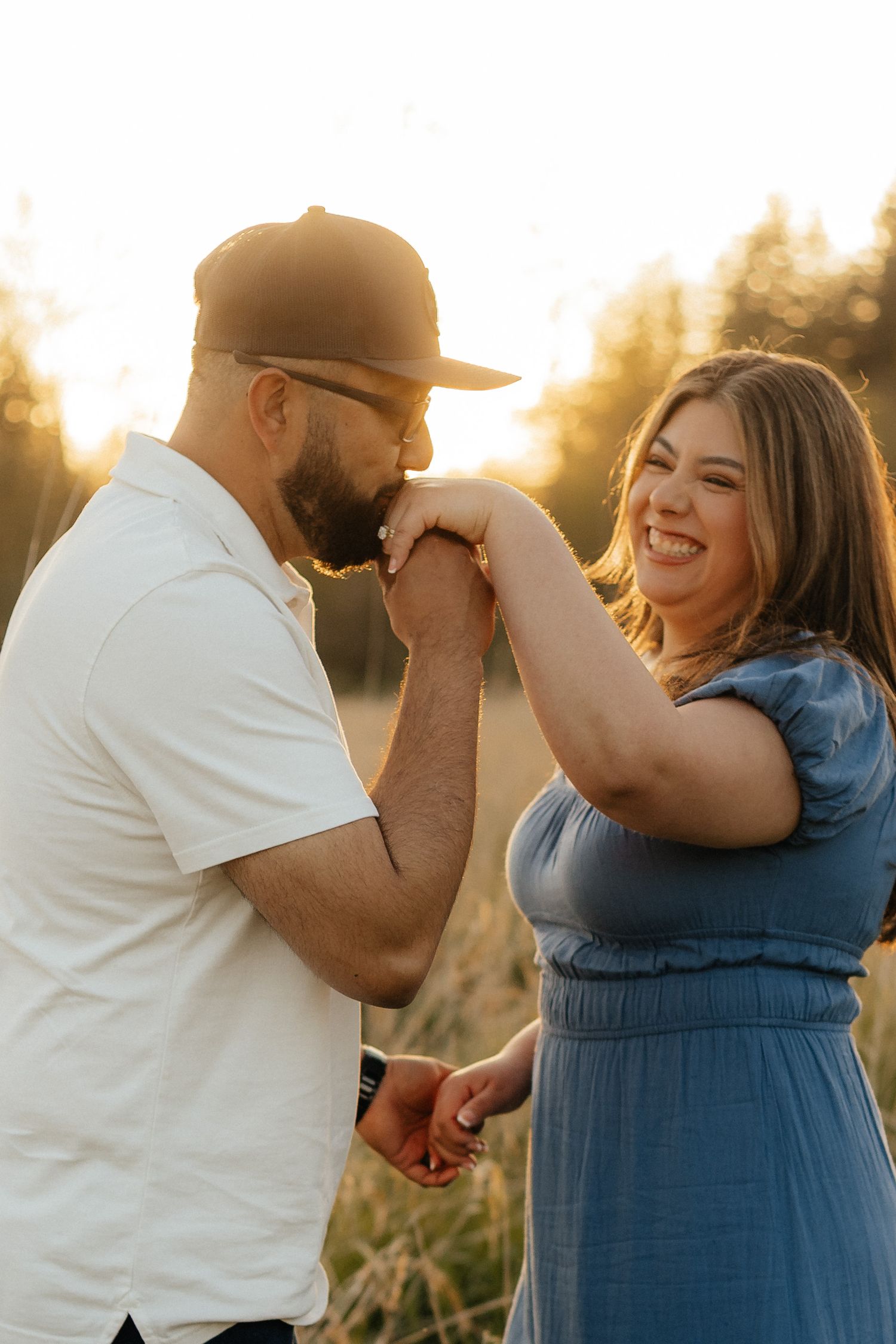 A romantic sunset photoshoot shows a couple sharing a joyful moment in a field during golden hour.