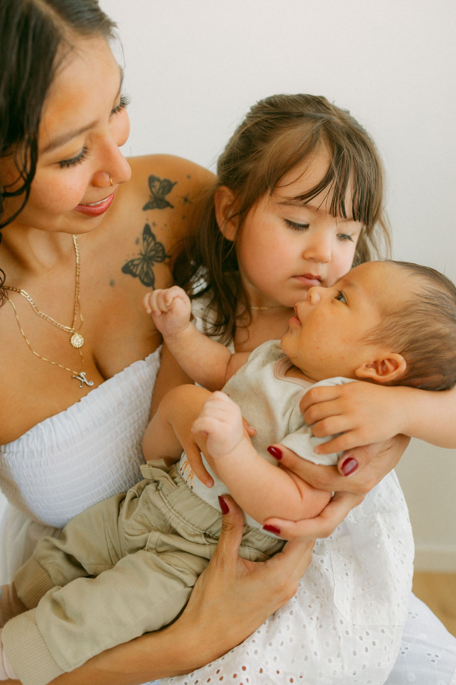 A tender moment shows parent and child embracing and playing together in white clothing against a light background.