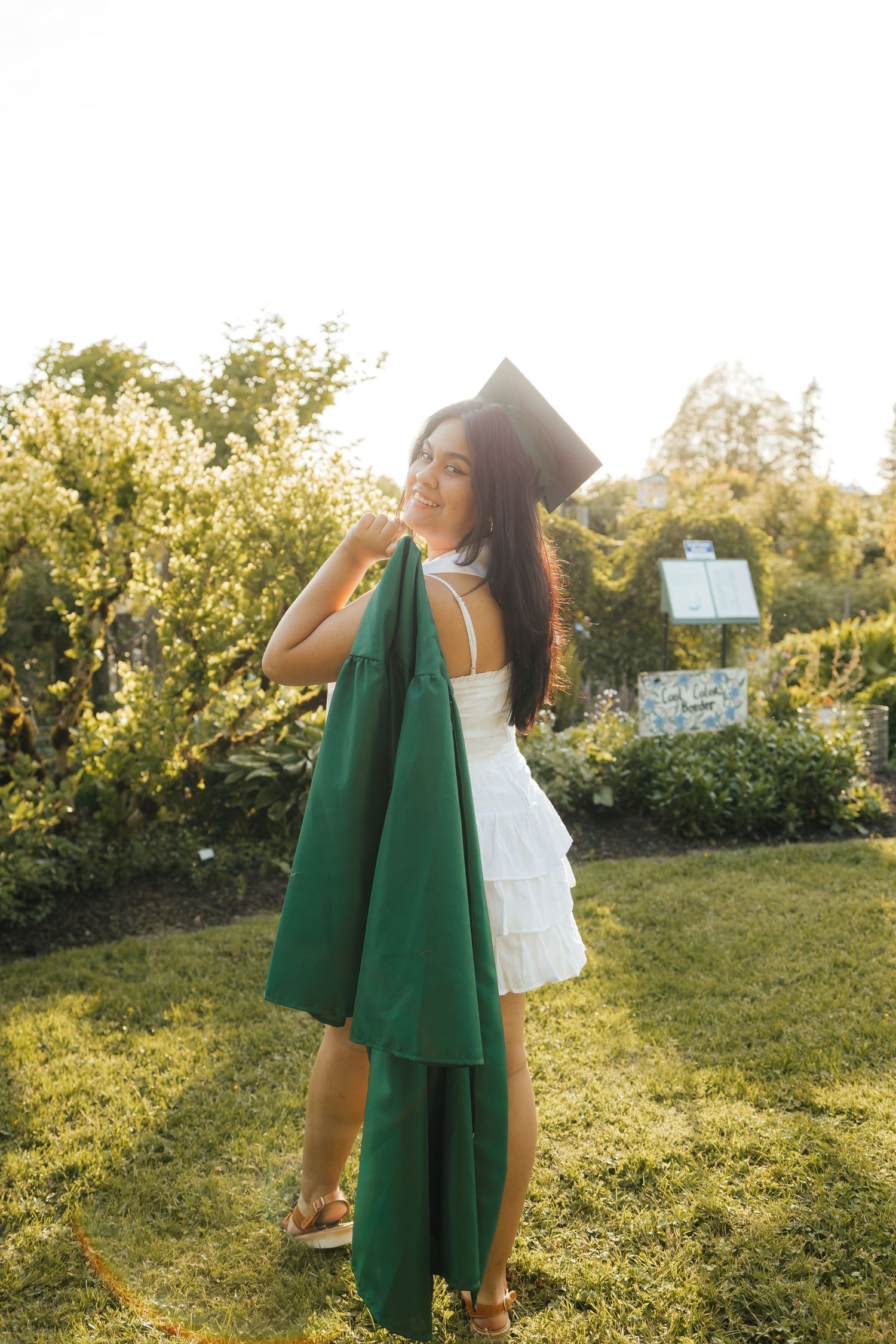 A person in a green cardigan dances in a sunlit garden during golden hour.
