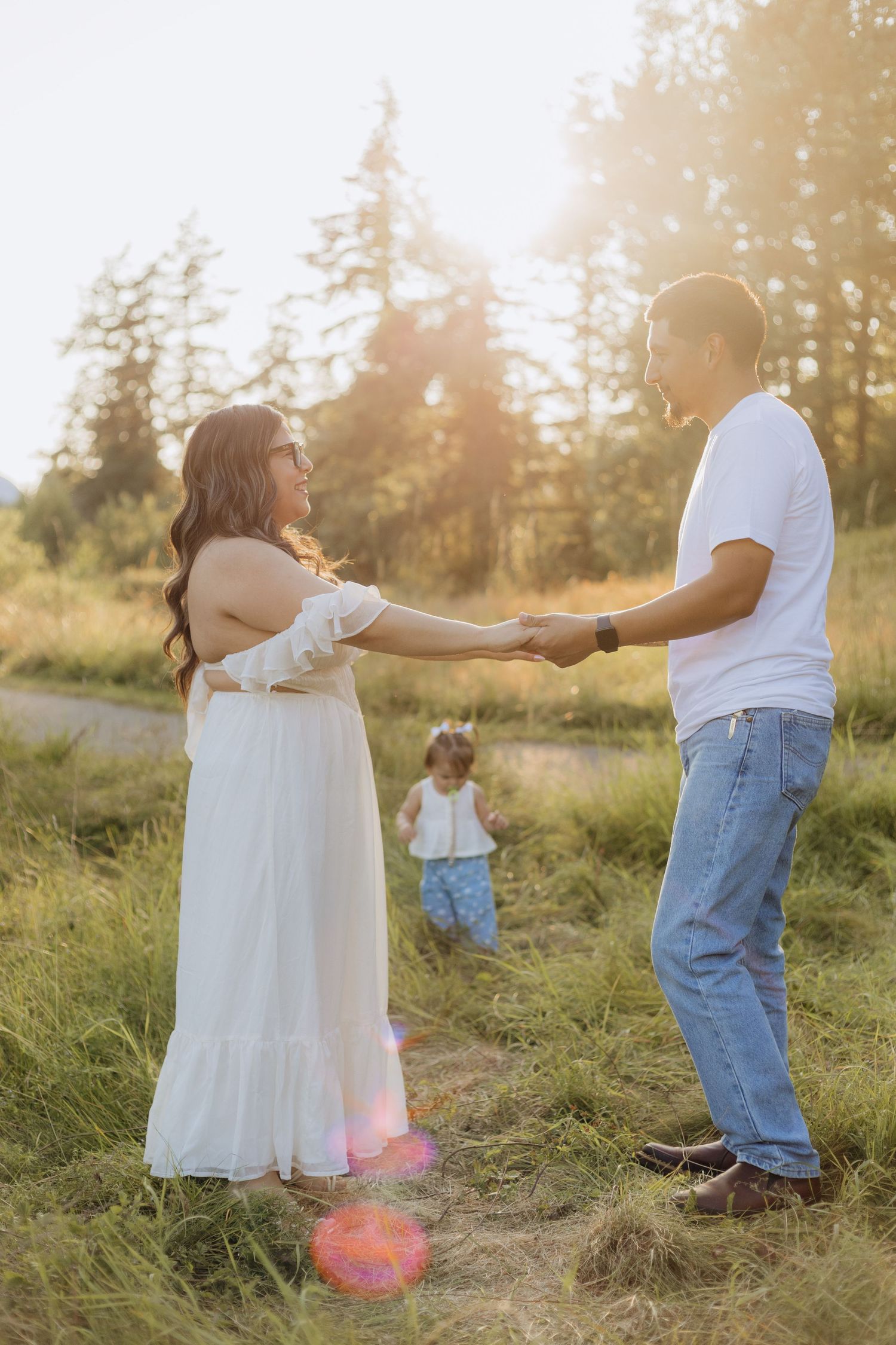 A couple dances together in a sunlit meadow during golden hour, creating a romantic silhouette among tall grasses.
