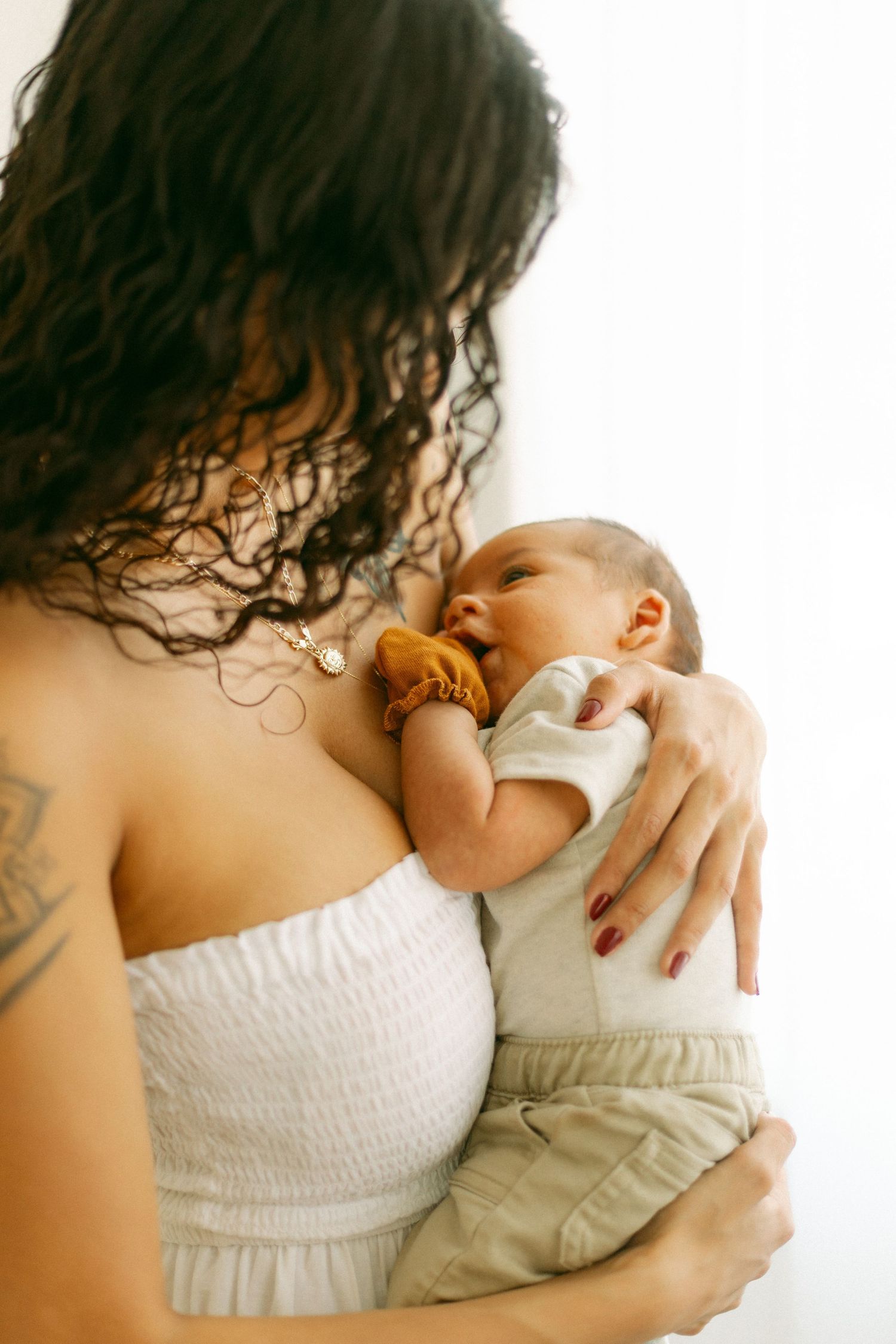 A tender moment showing someone in a white top gently cradling a sleeping infant against their chest.