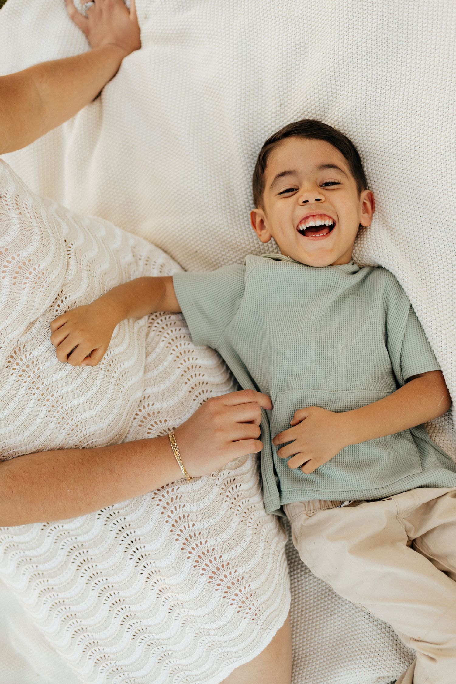 Sequence of photos showing playful laughter on white bedding in casual mint green clothing.