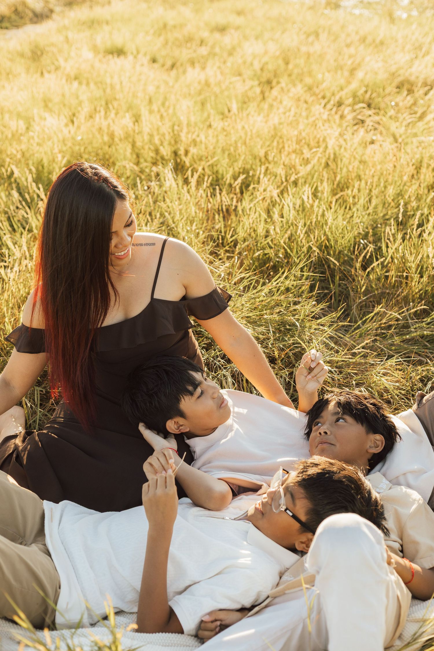 A group relaxes together in a sun-drenched golden wheat field during sunset, creating a warm and intimate moment.