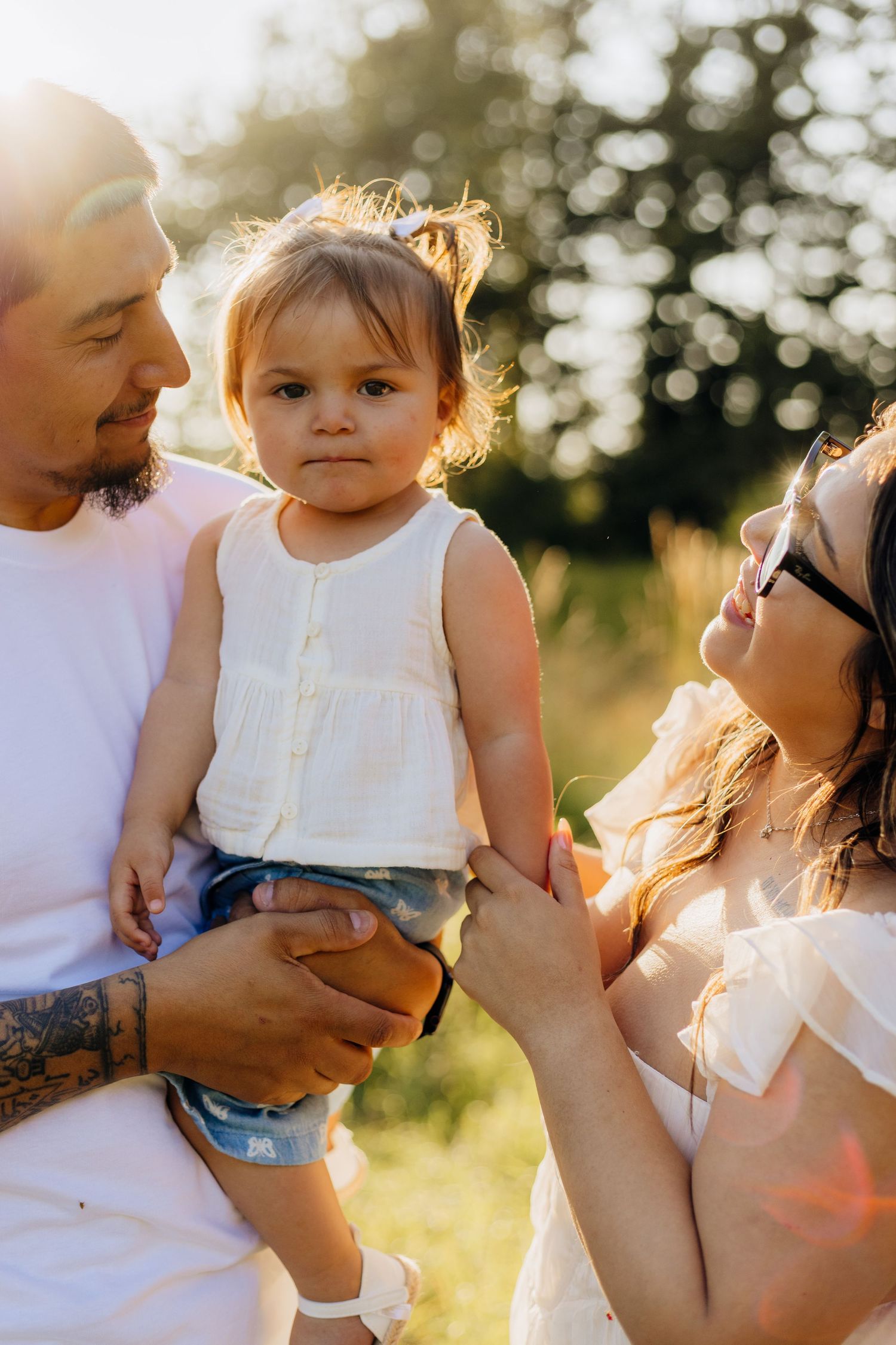 Family sharing tender moments together outdoors during golden hour while bathed in warm summer sunlight.