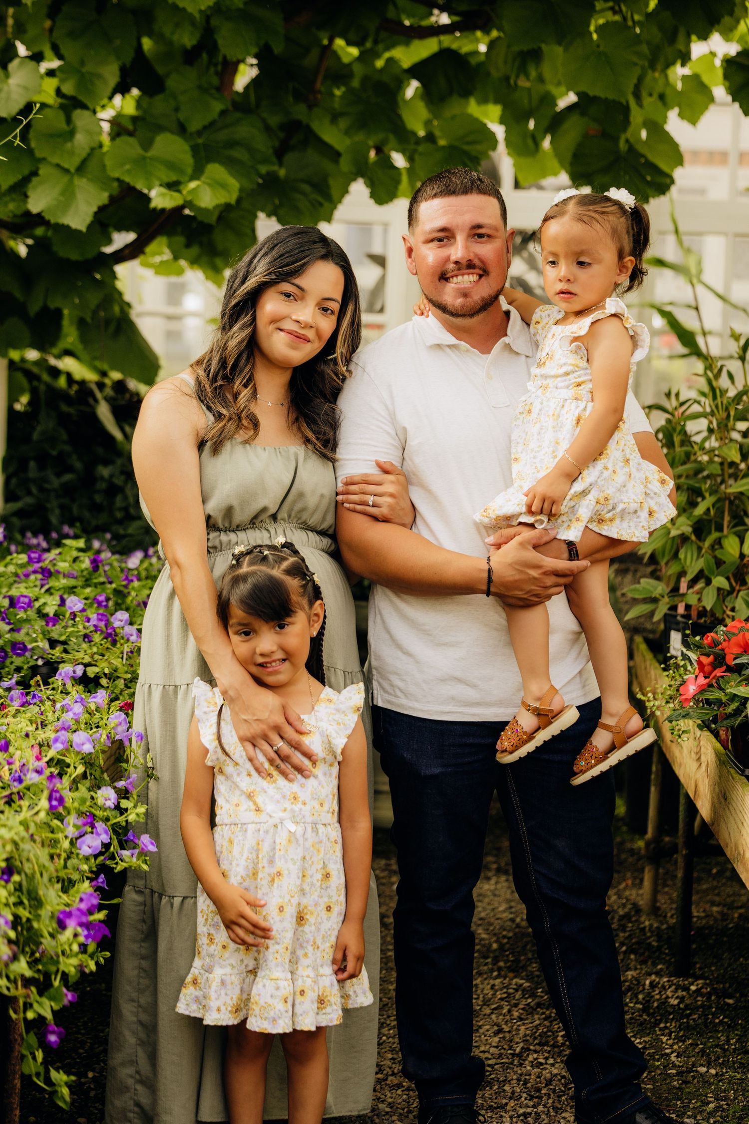 A family poses together in front of purple flowers and green foliage on a warm summer day.