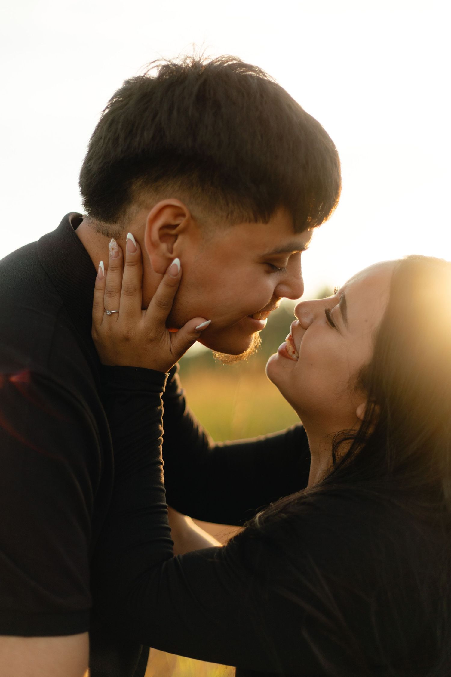 Two silhouettes share an intimate moment at sunset against a golden backdrop.