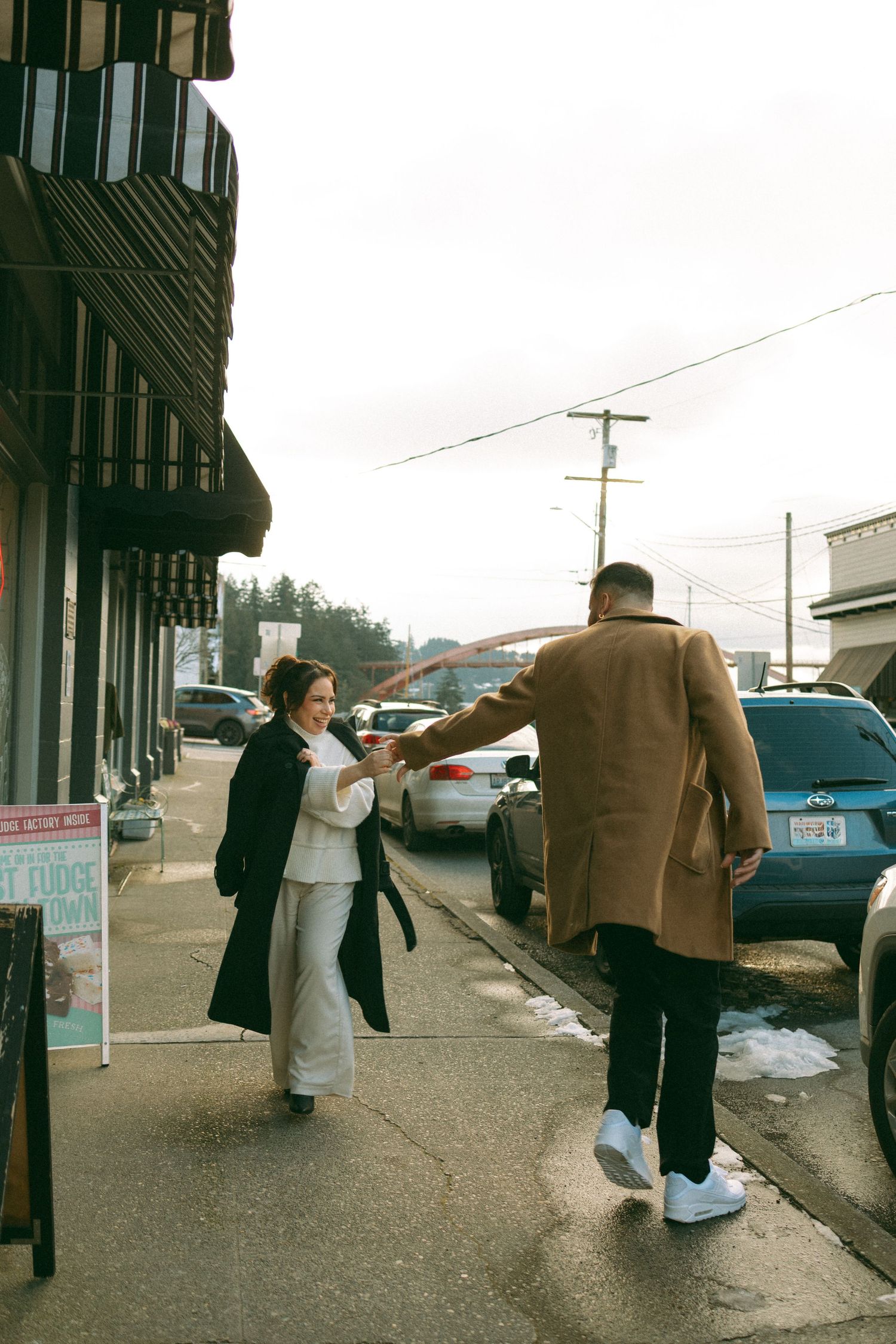 Couple walking down a sidewalk in an urban setting on an overcast day.