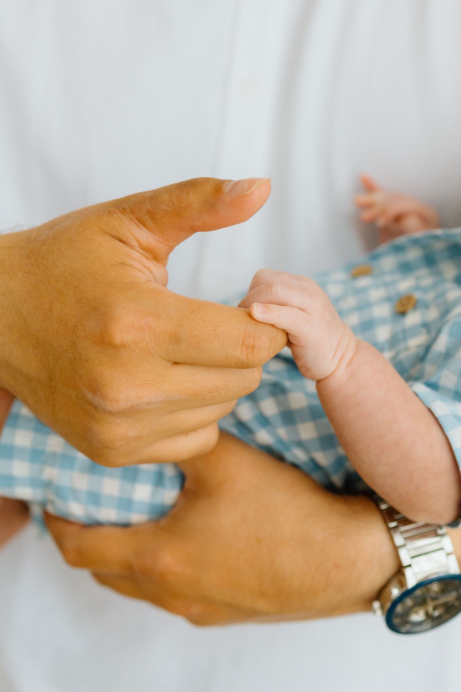 Close-up sequence of hands exchanging a wristwatch or timepiece in gentle movement against a light background.