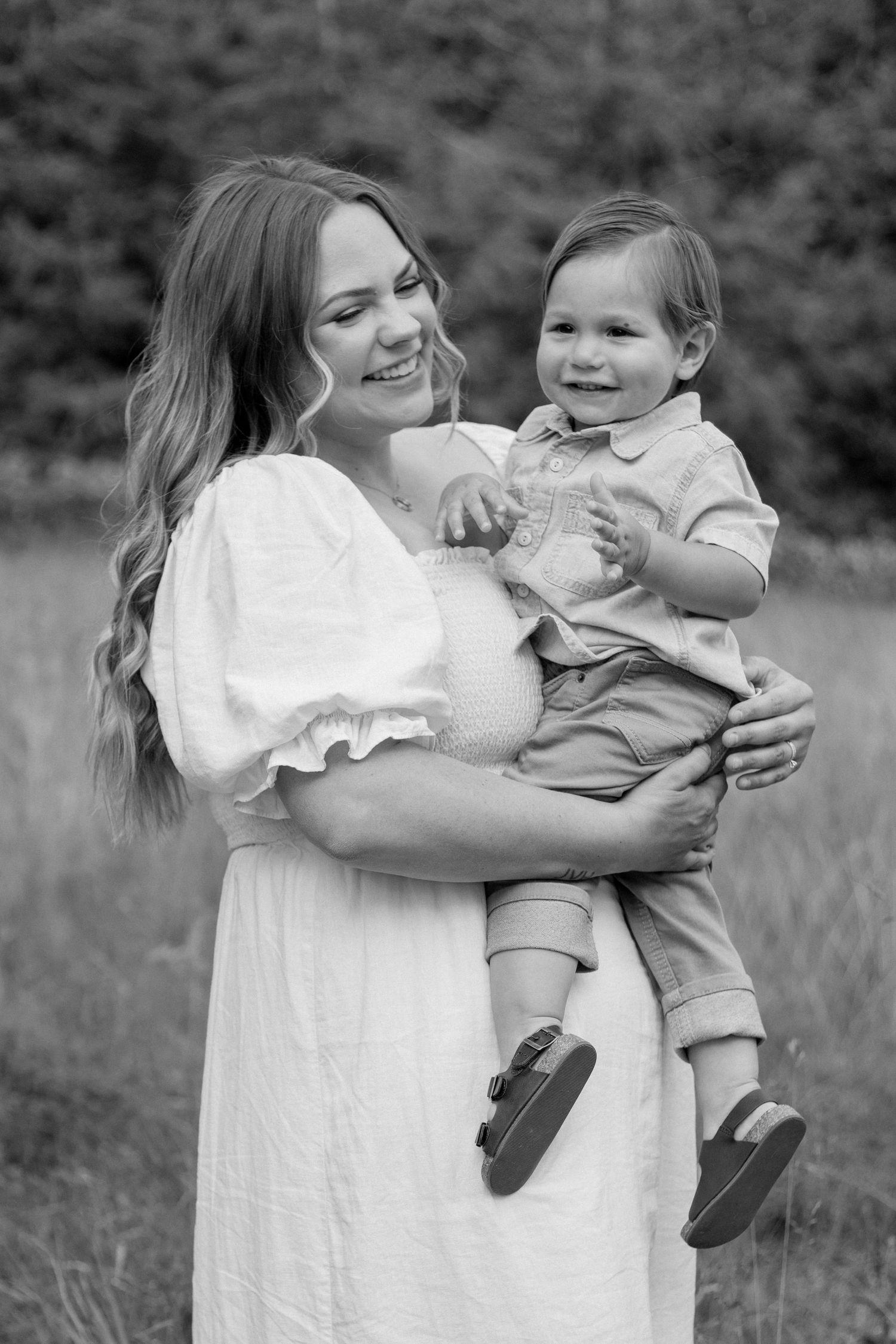 A loving embrace between an adult in a white dress and a child in tan clothing outdoors in black and white.