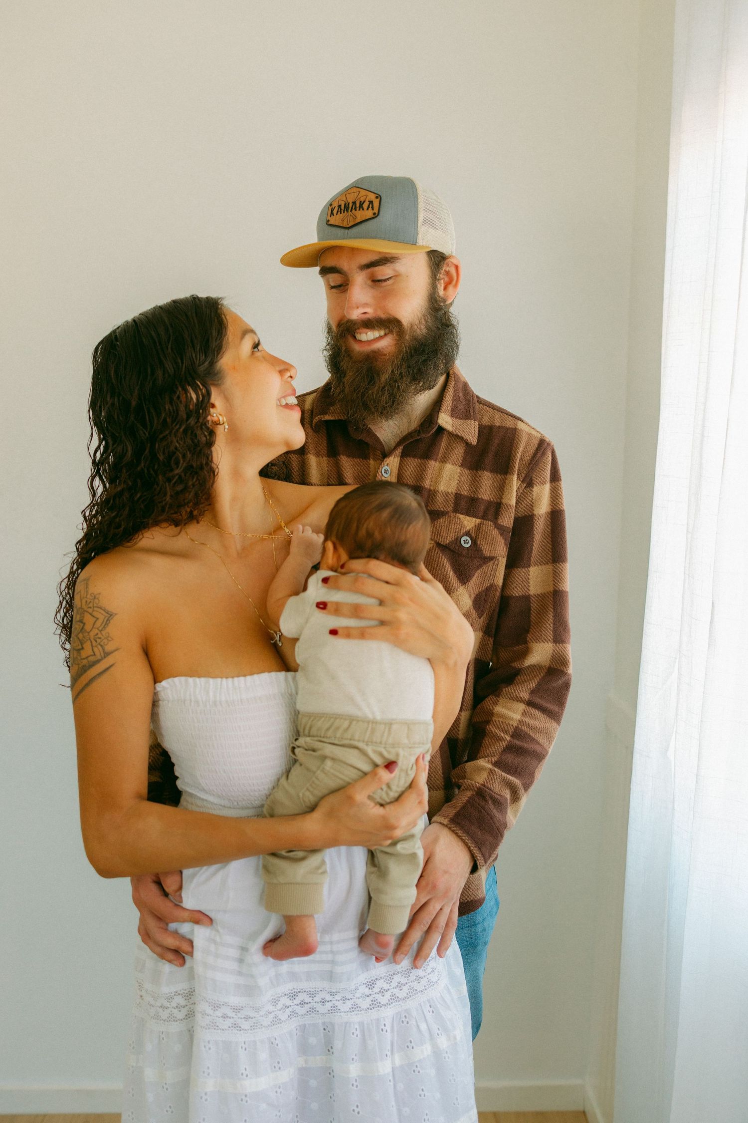 Family poses together in an intimate series of indoor portraits showing affectionate moments in casual home setting.