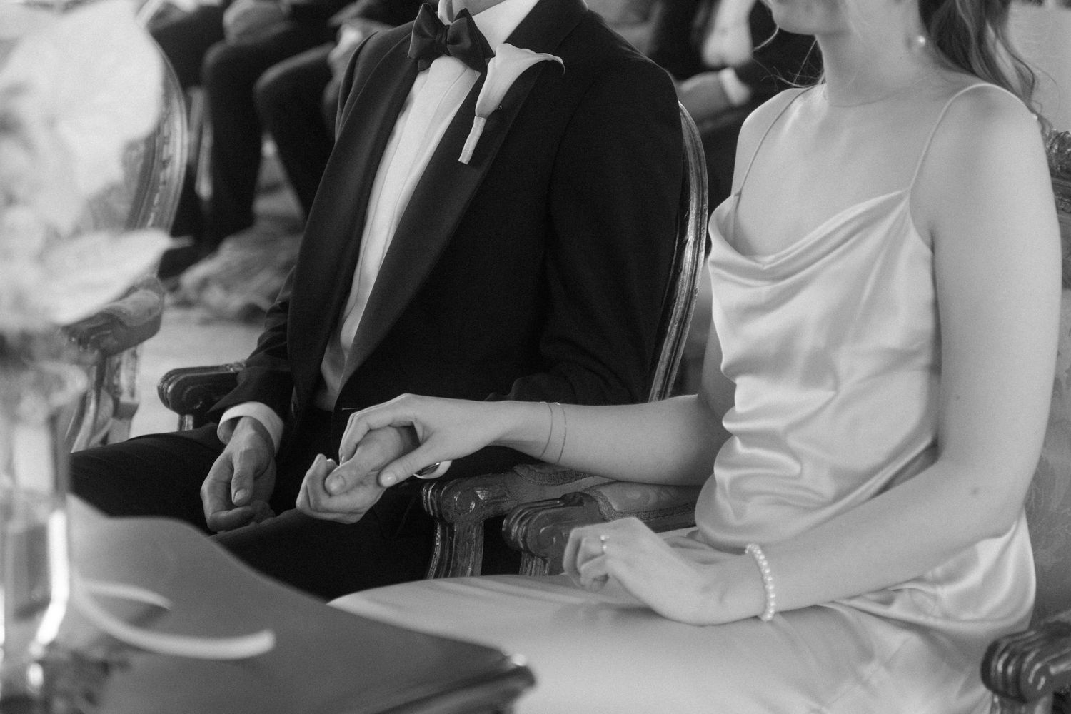 Close-up of formal attire and hands during an elegant wedding ceremony.