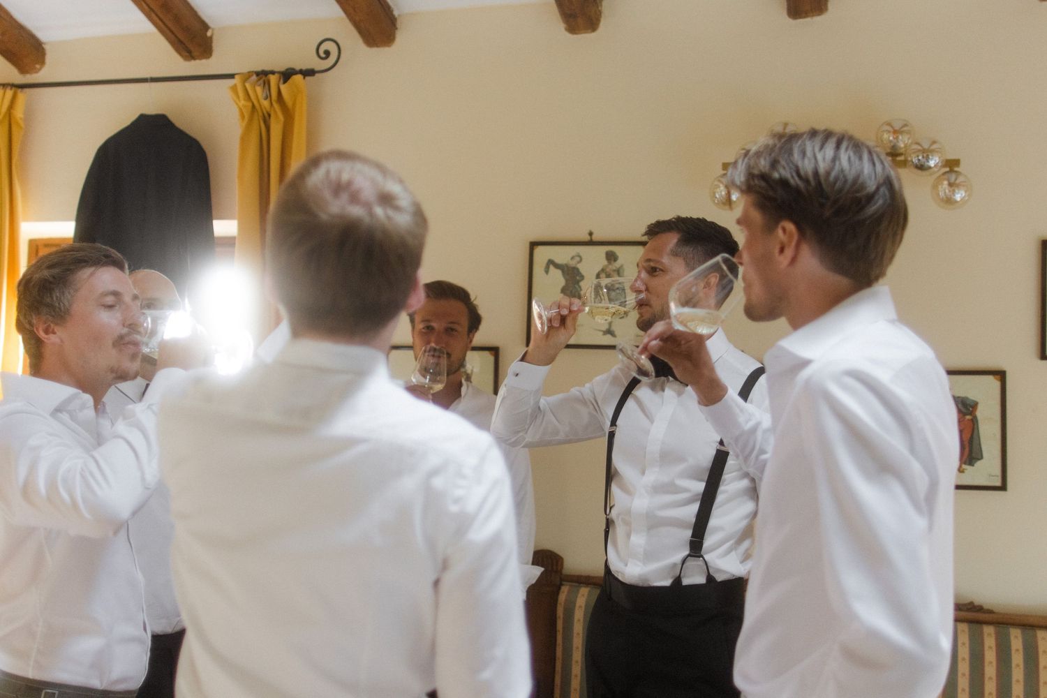 People in white shirts and formal wear interact in a room with wooden ceiling beams.