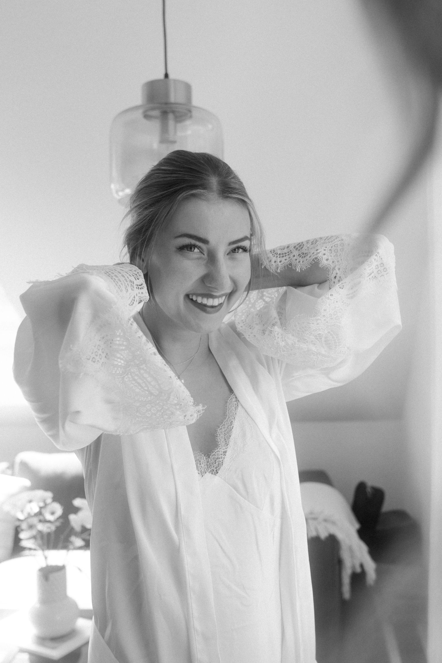 Black and white portrait of person in white robe smiling near window.