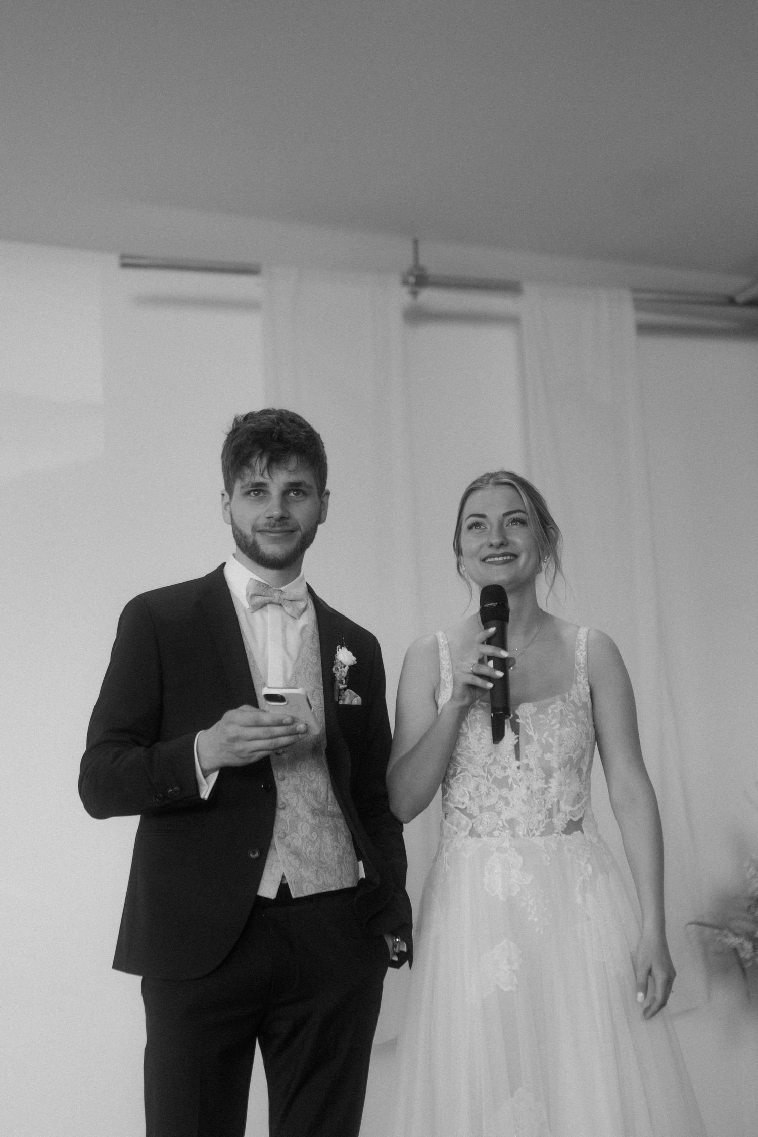 Couple shares microphones during wedding reception speech.