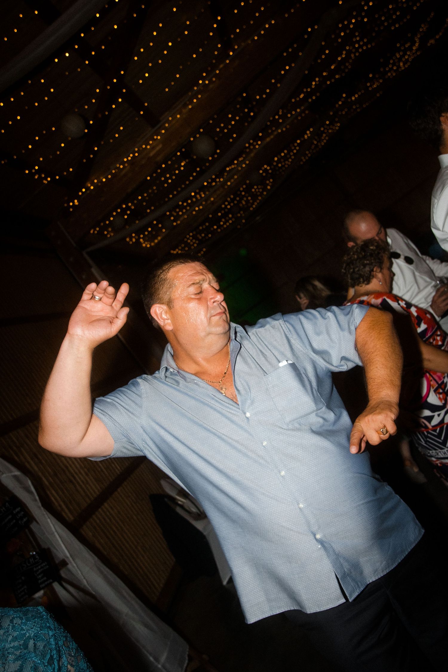 Person in light blue shirt dancing energetically at what appears to be a party or celebration.