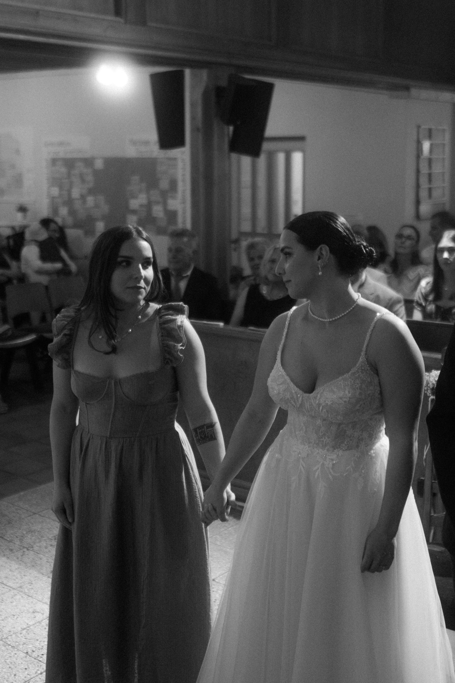 A tender moment between two people holding hands during an indoor wedding celebration.