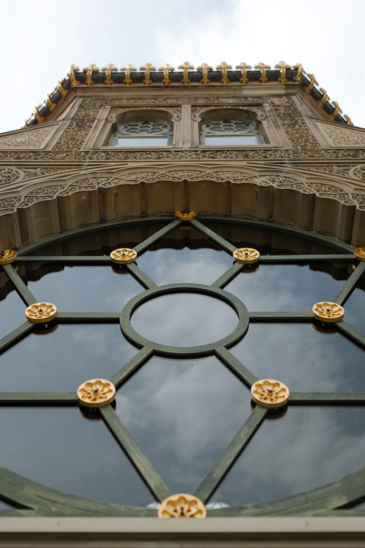 Ornate architectural window detail with gold medallions and geometric metalwork pattern.