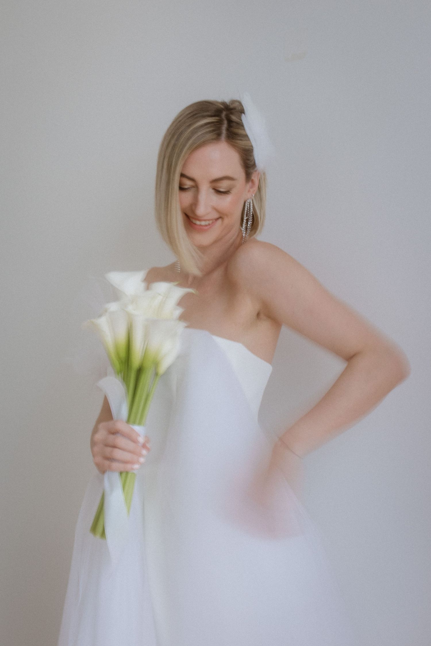 Candid portrait of bride holding calla lilies in white wedding gown.