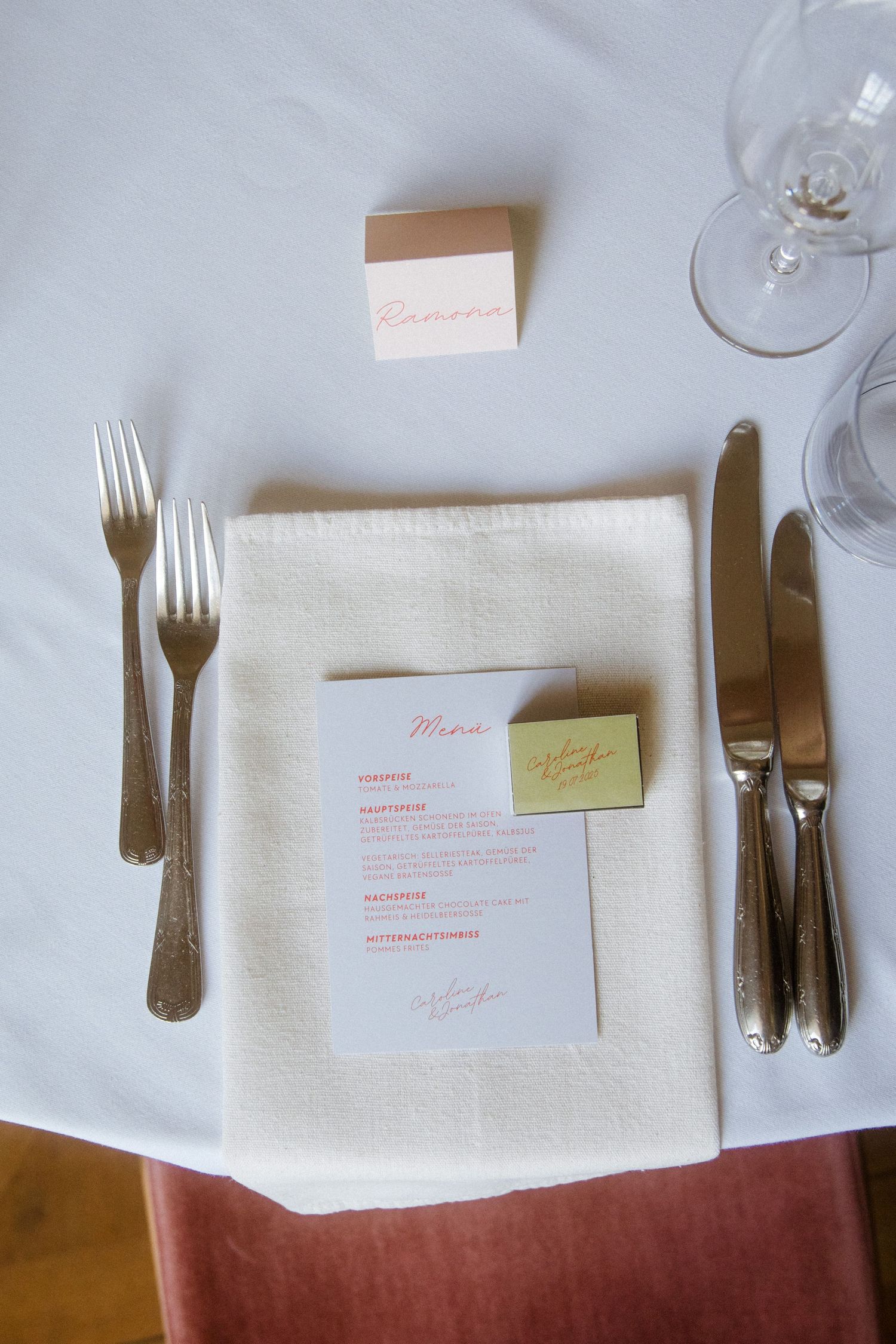 Wedding place setting with white napkin, silverware and menu card on table.