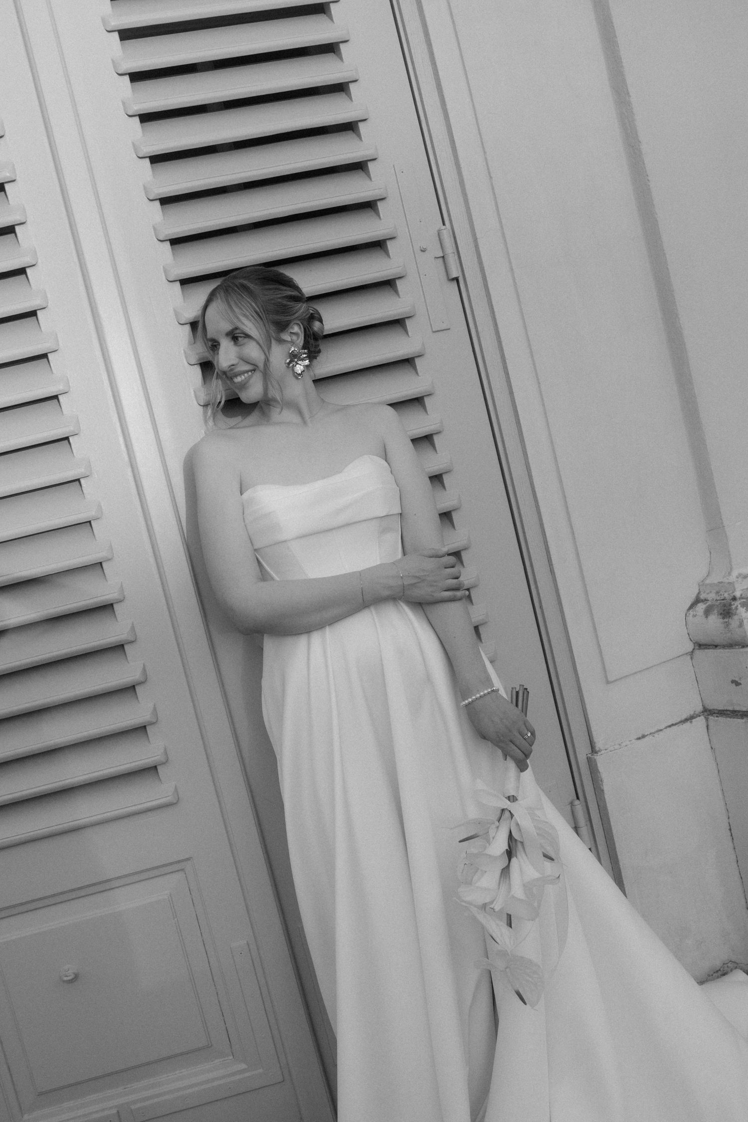 Black and white portrait of bride with flowing dress against architectural details.
