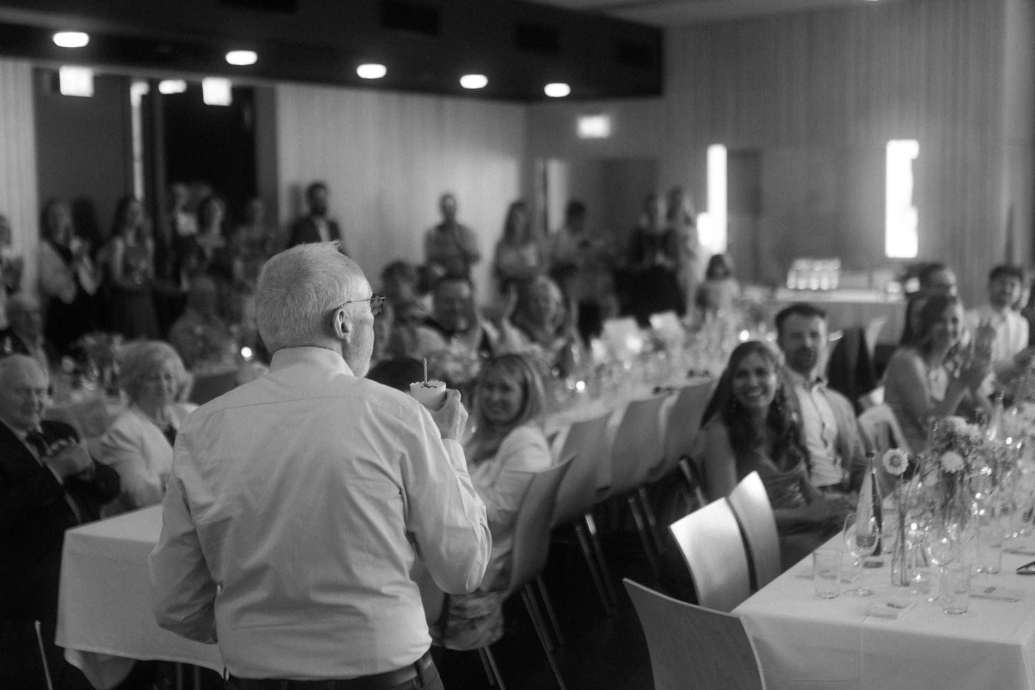 Black and white photo of wedding reception dinner with guests seated at tables.
