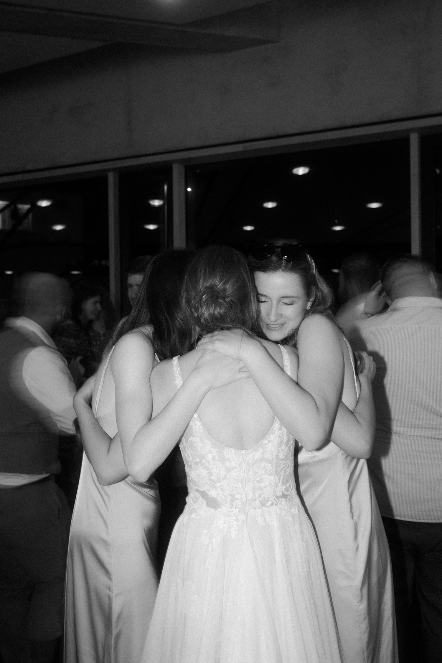 Black and white photo capturing emotional embrace during wedding reception.