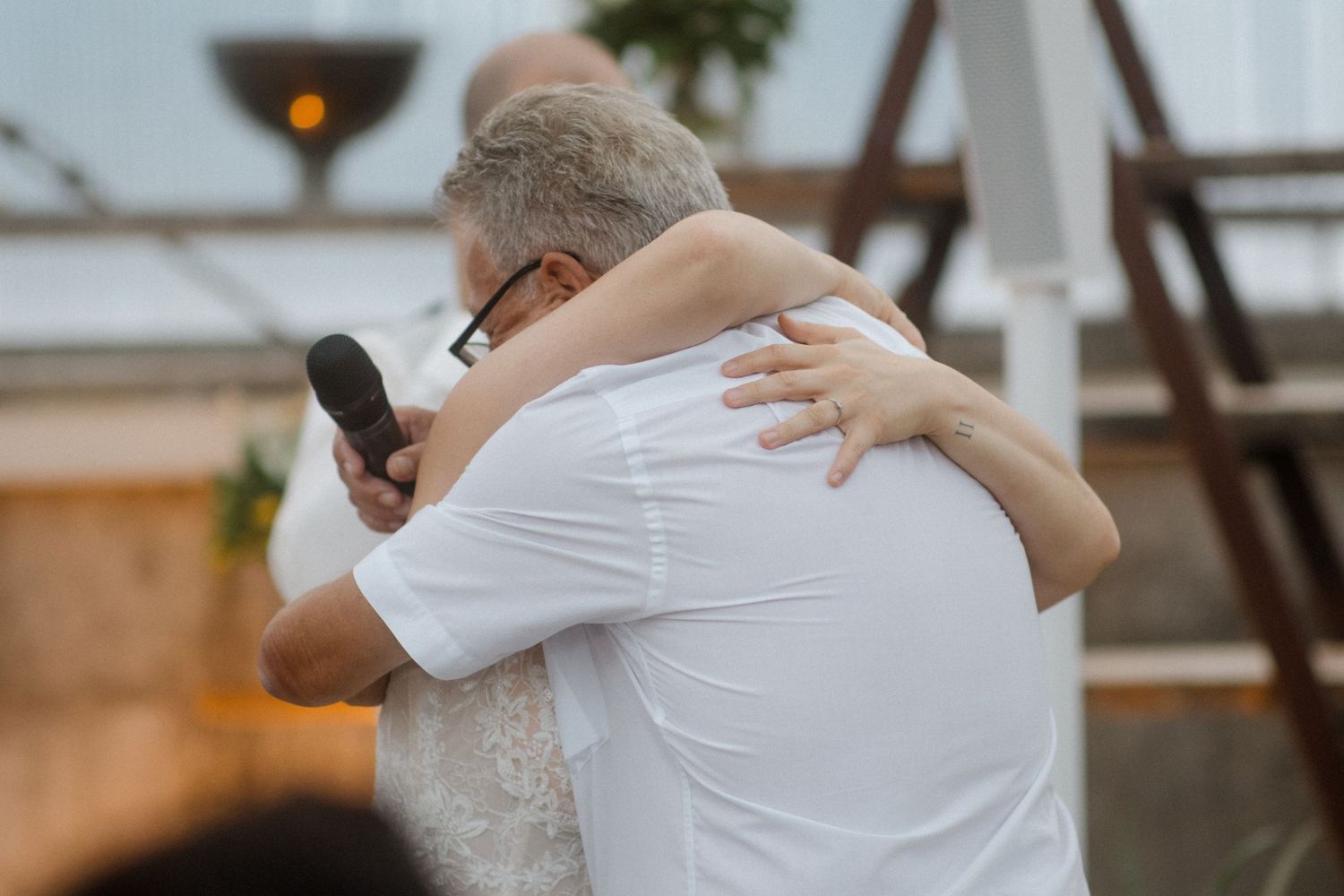 An emotional embrace shared during a wedding ceremony outdoors at sunset.