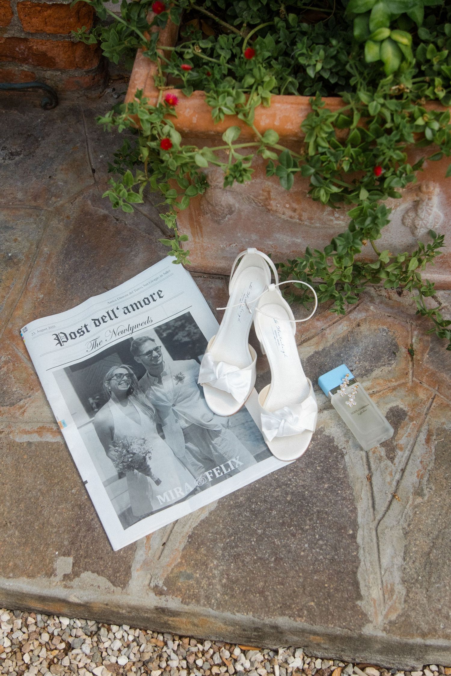 White wedding shoes and vintage photographs arranged on stone patio with climbing plants.