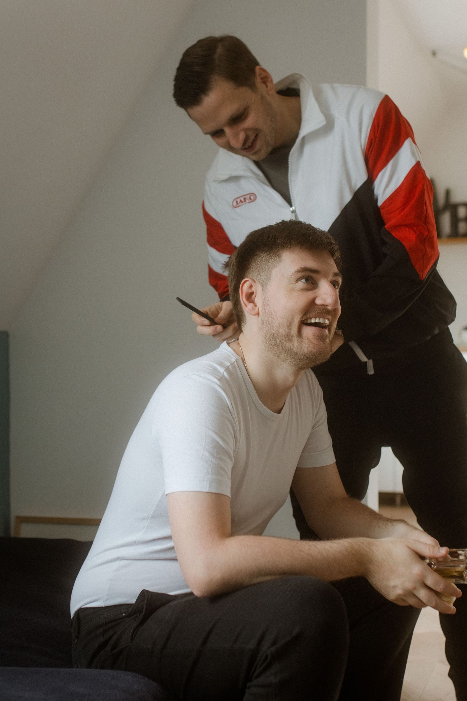A candid moment showing a hairstyling session in casual attire.