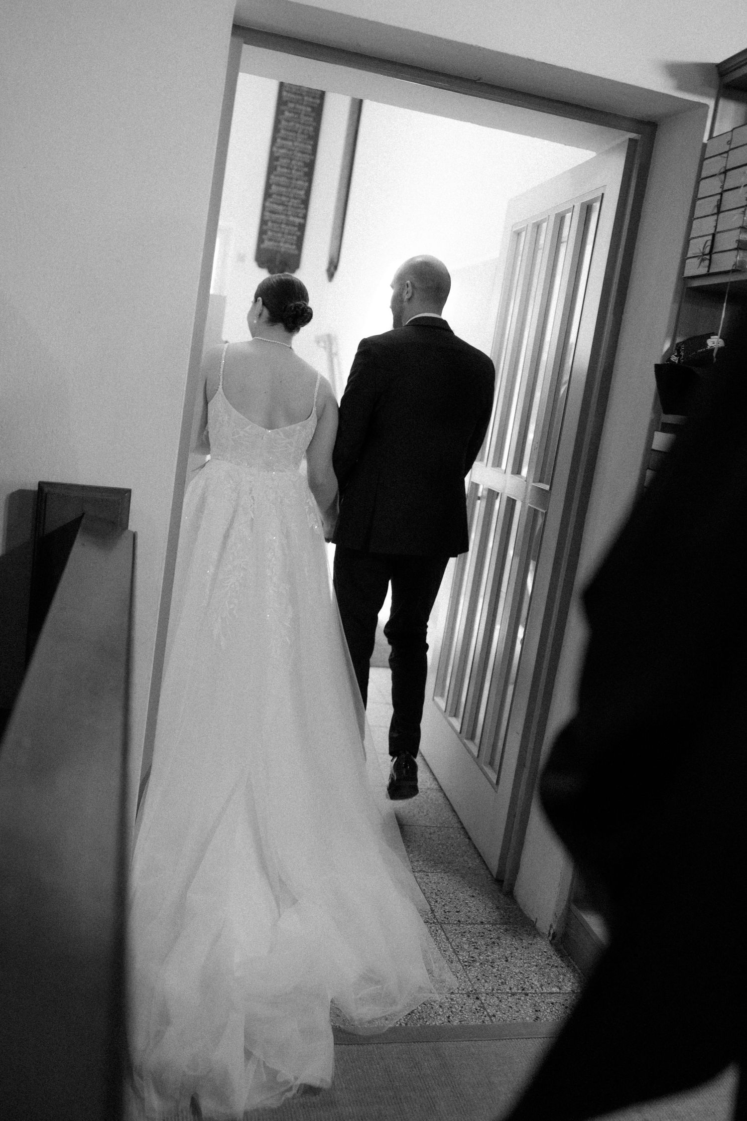 Black and white shot of couple walking through doorway after ceremony.